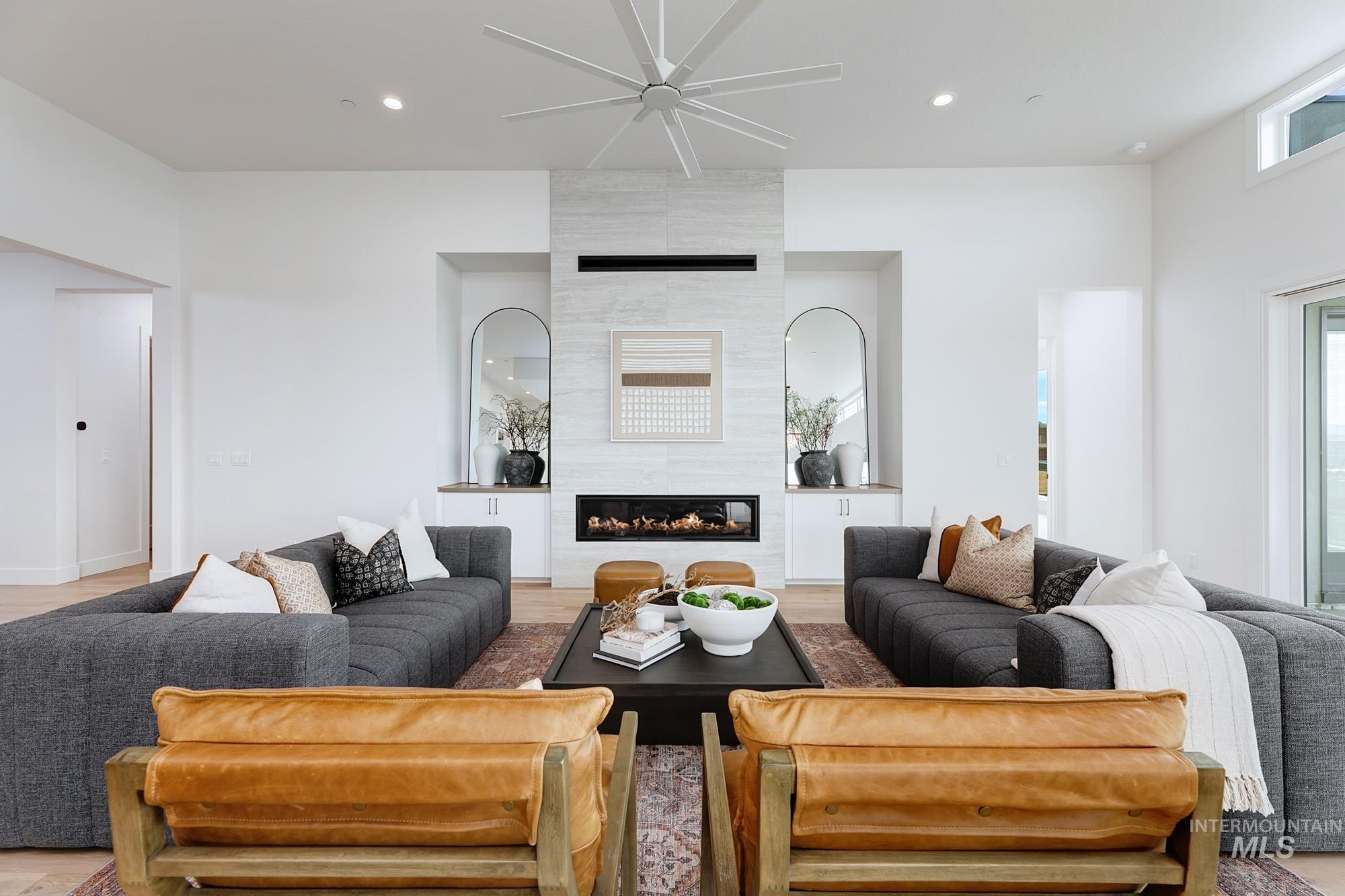 Living area with a tile fireplace, ceiling fan, recessed lighting, and light wood finished floors