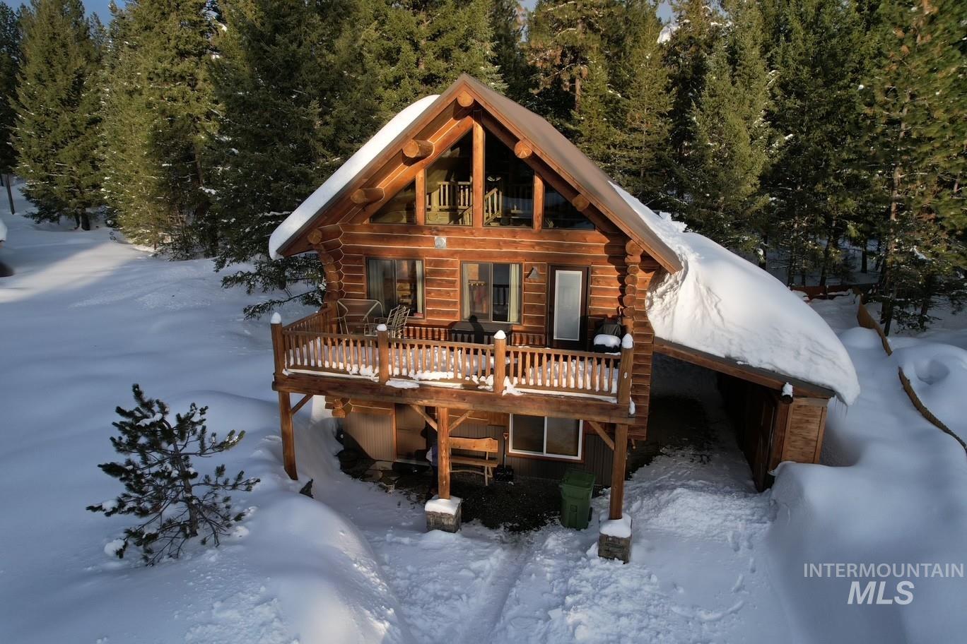 Snow covered rear of property featuring a deck and log exterior