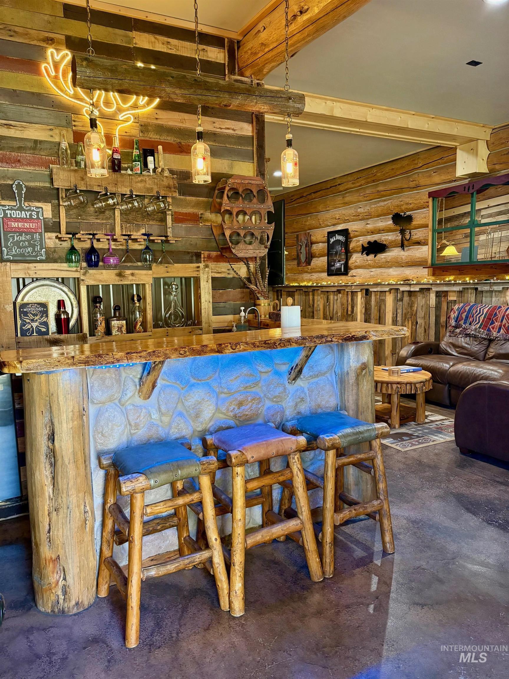 Bar area with finished concrete flooring, beam ceiling, and rustic walls