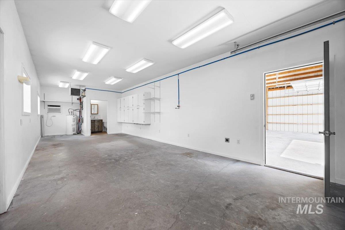 Garage featuring electric water heater and an AC wall unit