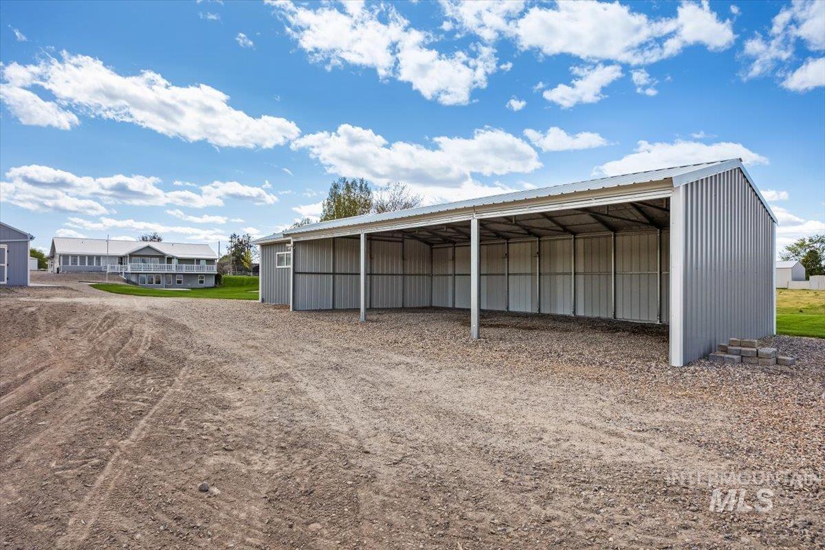 View of pole building featuring a carport and dirt driveway