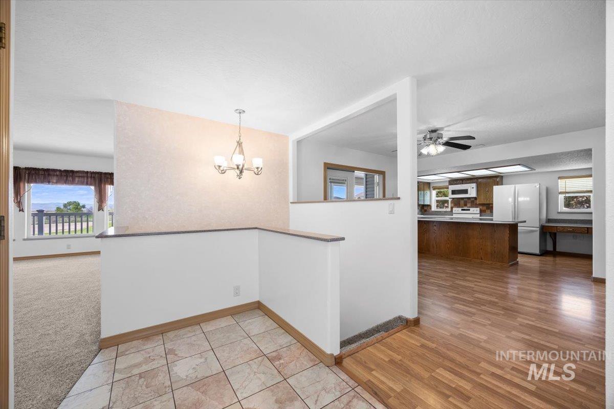 Unfurnished dining area with a ceiling fan, a chandelier, and plenty of natural light