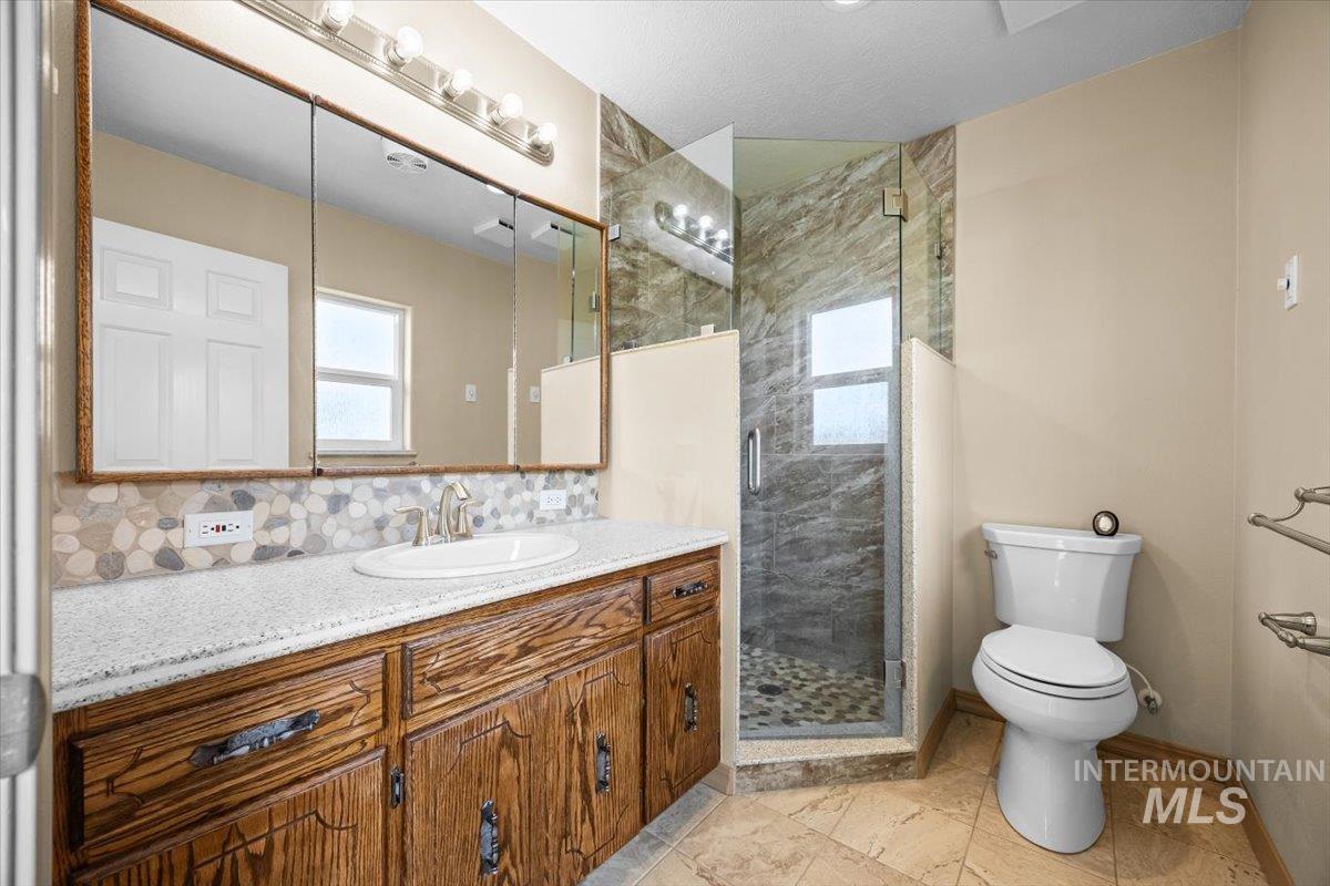 Full bathroom with a stall shower, vanity, and decorative backsplash