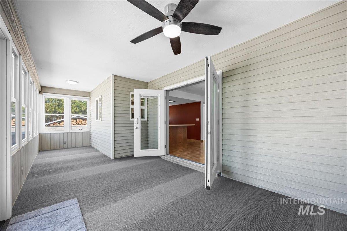 Unfurnished sunroom with wood walls and carpet