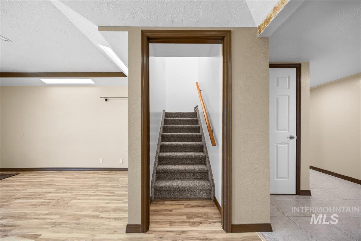 Staircase with wood finished floors and a textured ceiling