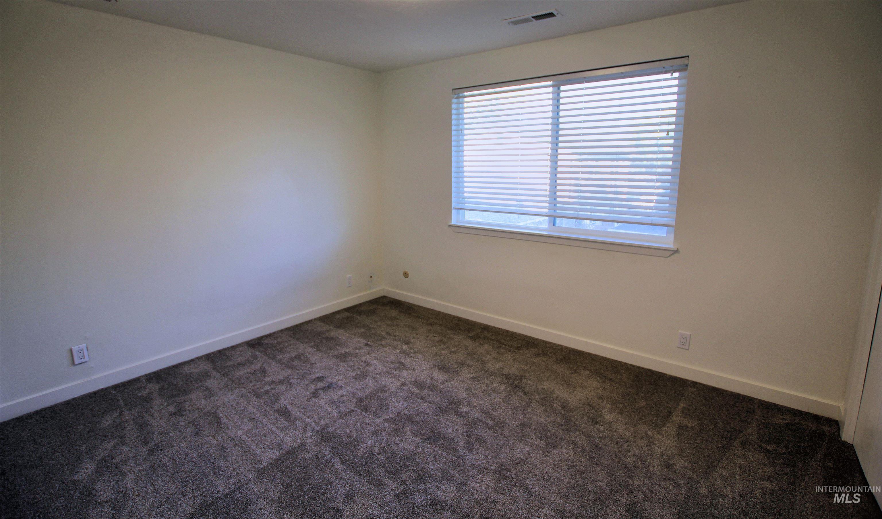 Empty room with dark carpet and baseboards