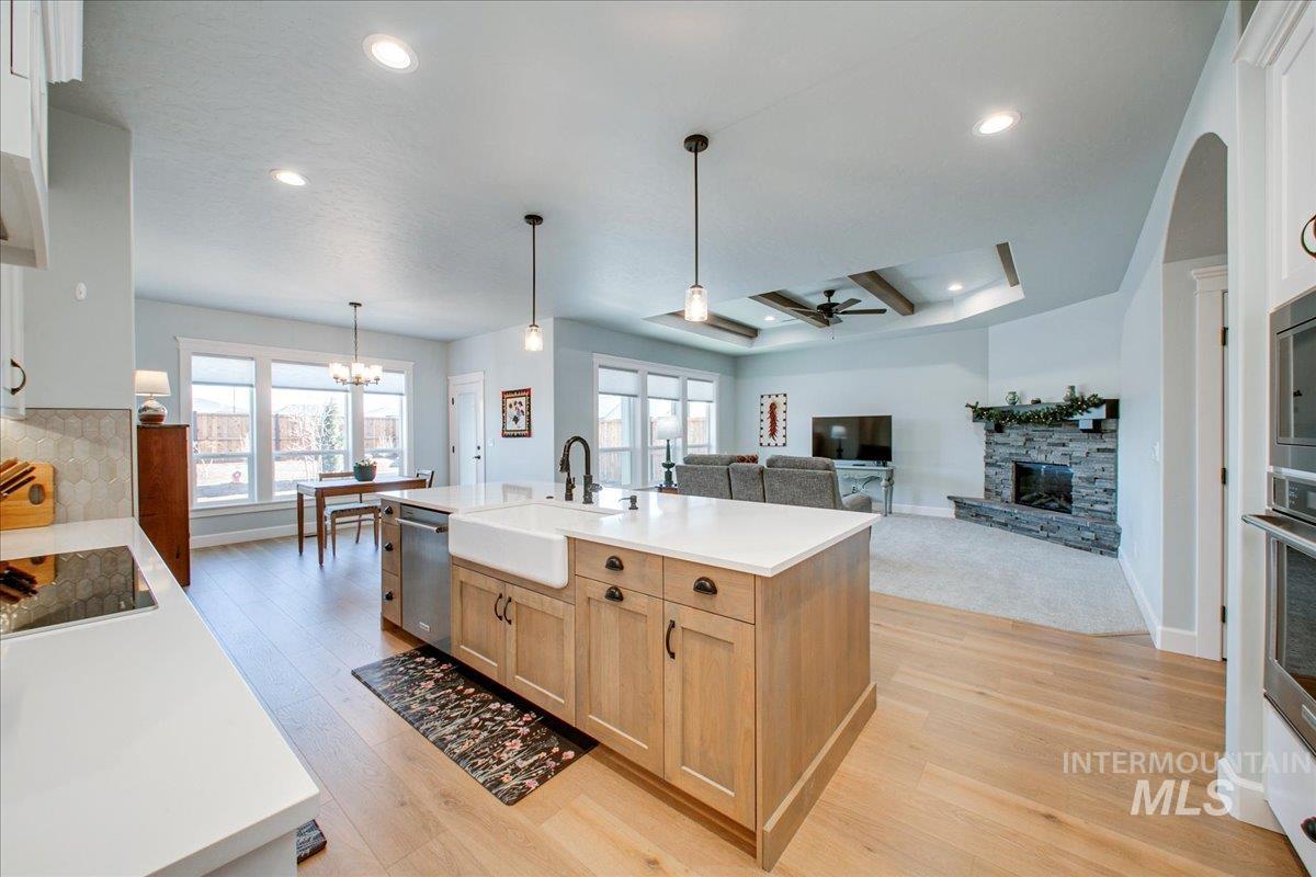 Kitchen with a stone fireplace, decorative light fixtures, light wood-type flooring, ceiling fan, and recessed lighting
