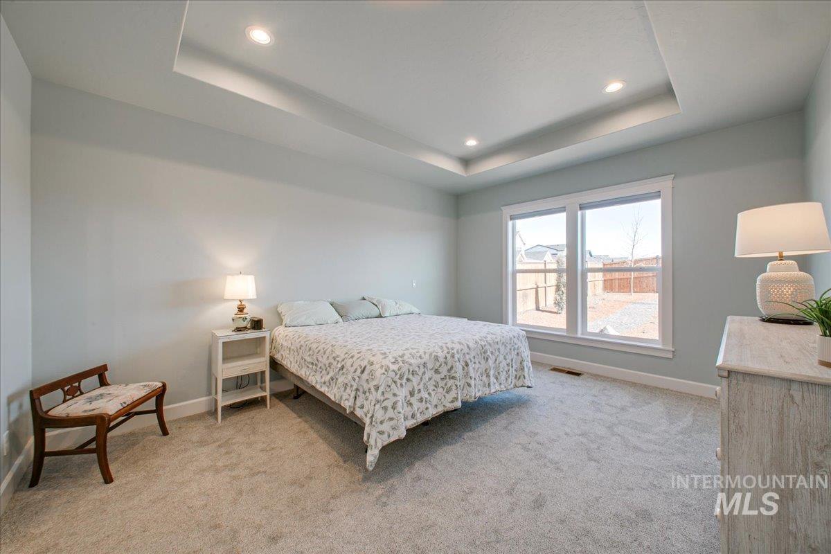Bedroom featuring a raised ceiling, light colored carpet, and recessed lighting