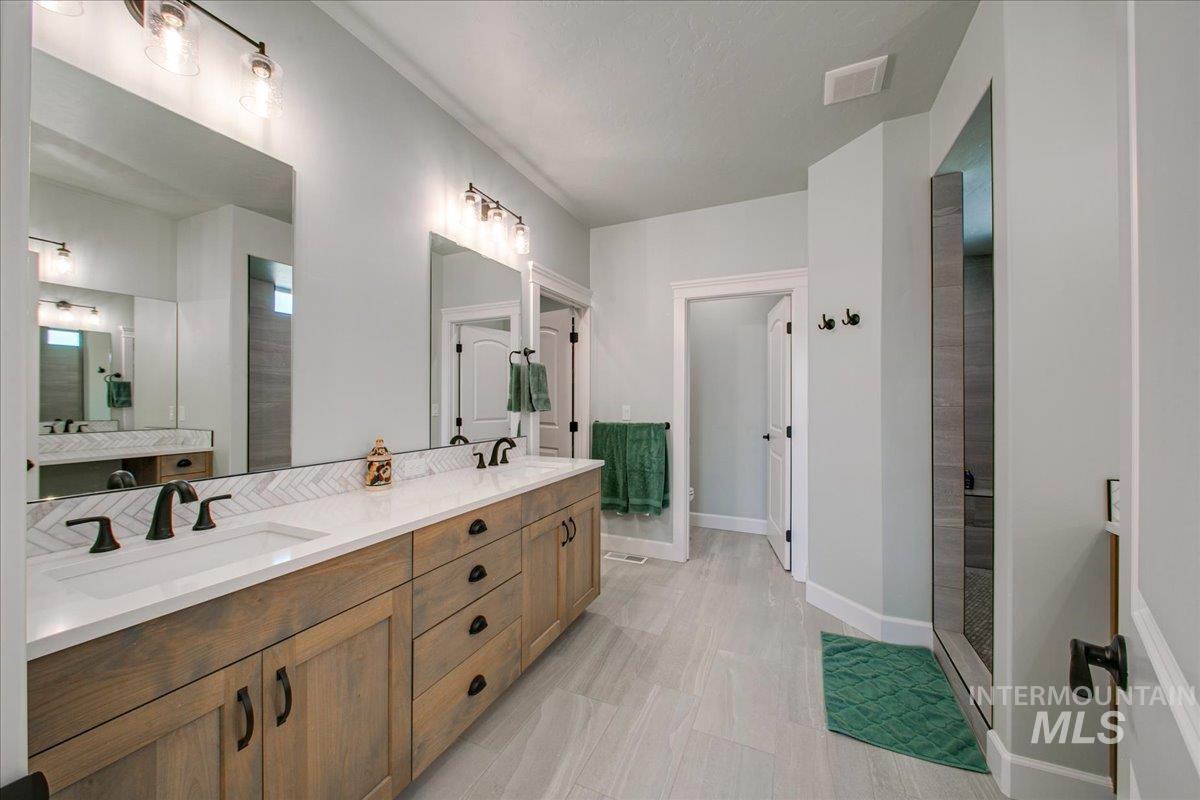 Full bath featuring a double vanity and a tiled walk-in shower.