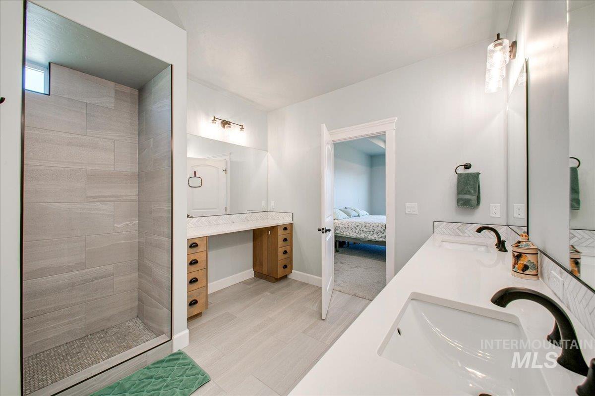 Ensuite bathroom with double vanity, walk in shower, and light wood finished floors
