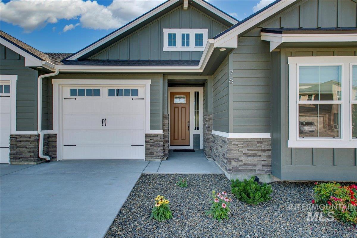 Doorway to property featuring stone siding, board and batten siding, and concrete driveway