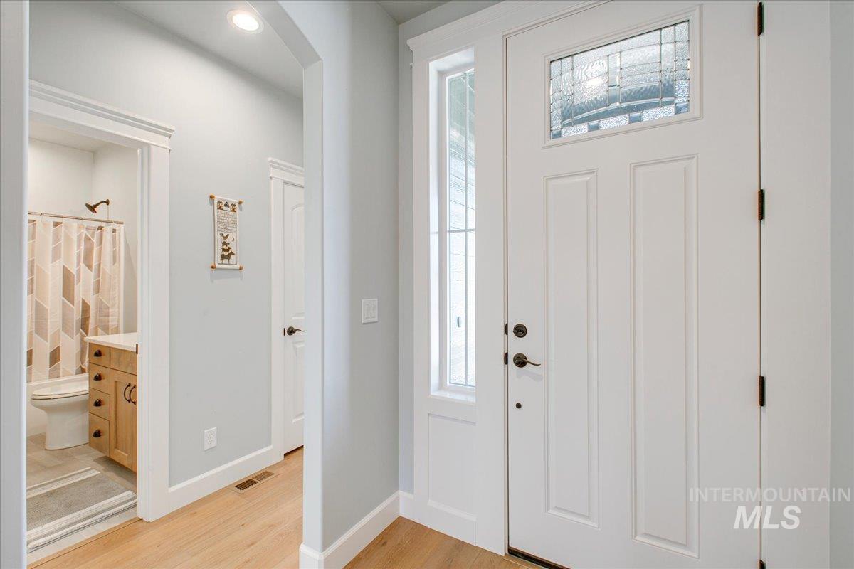 Foyer with plenty of natural light, arched walkways, and light wood-type flooring