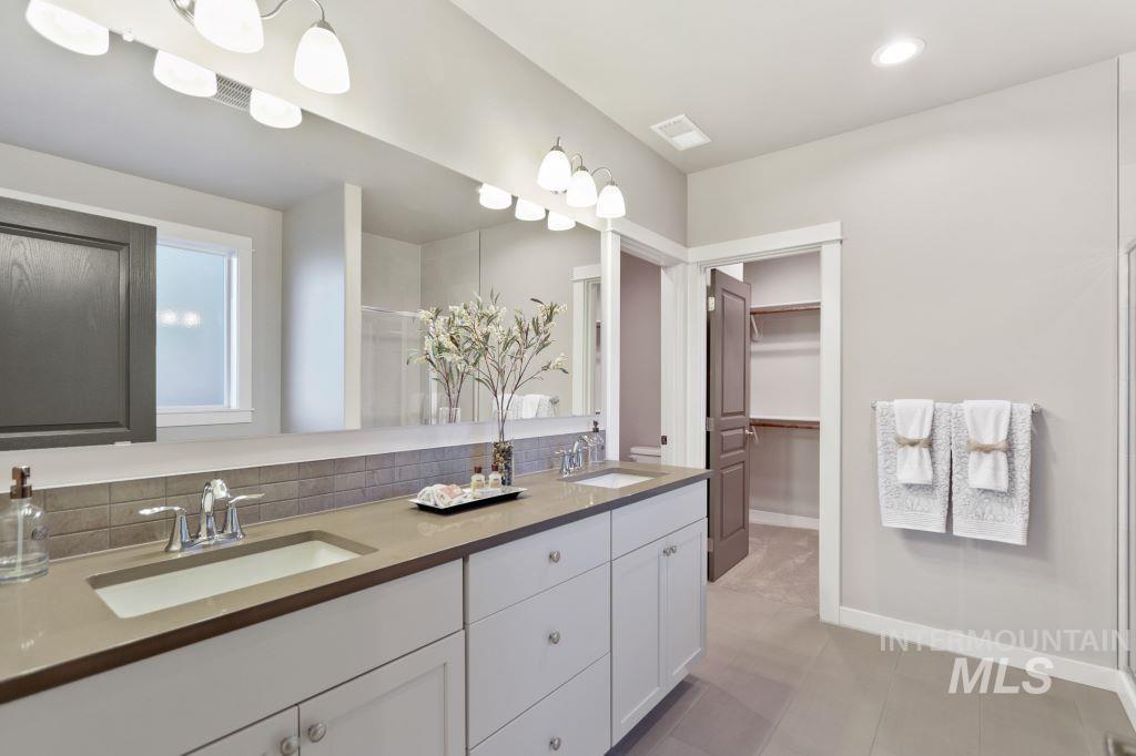Full bath with a shower stall, double vanity, backsplash, a spacious closet, and recessed lighting