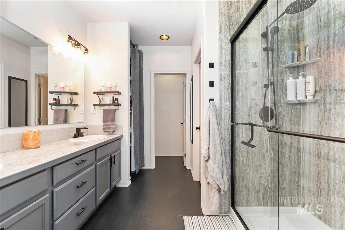Full bathroom featuring double vanity and a shower stall