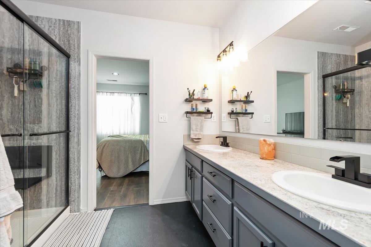 Bathroom featuring connected bathroom, a stall shower, and double vanity