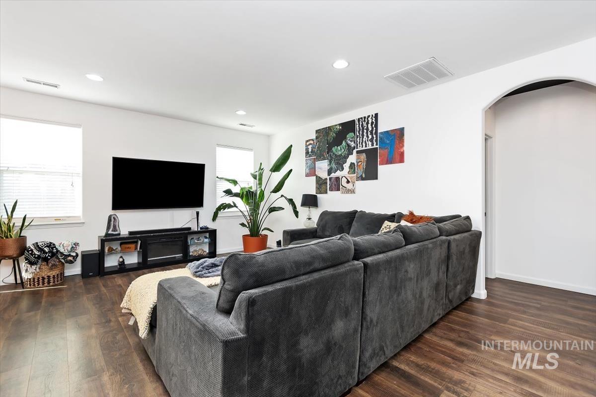 Living room featuring arched walkways, dark wood-style floors, and recessed lighting