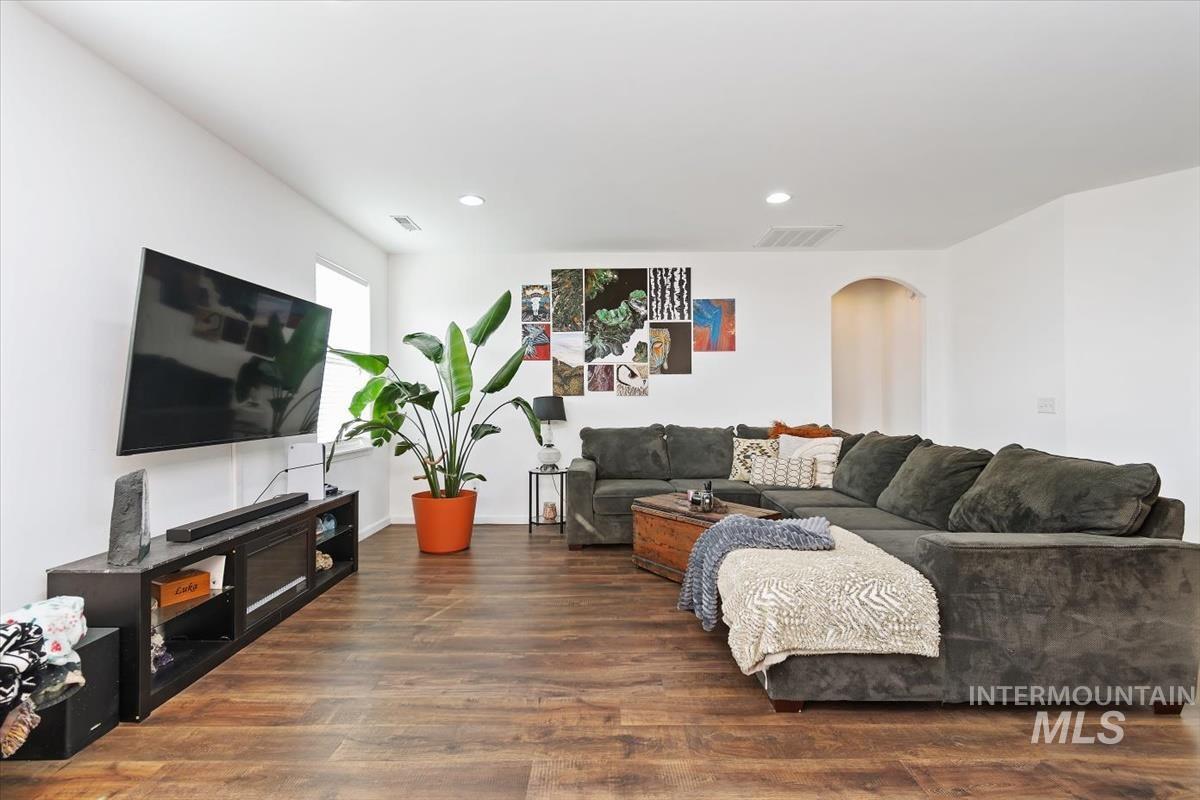 Living area featuring arched walkways, dark wood-style flooring, and recessed lighting