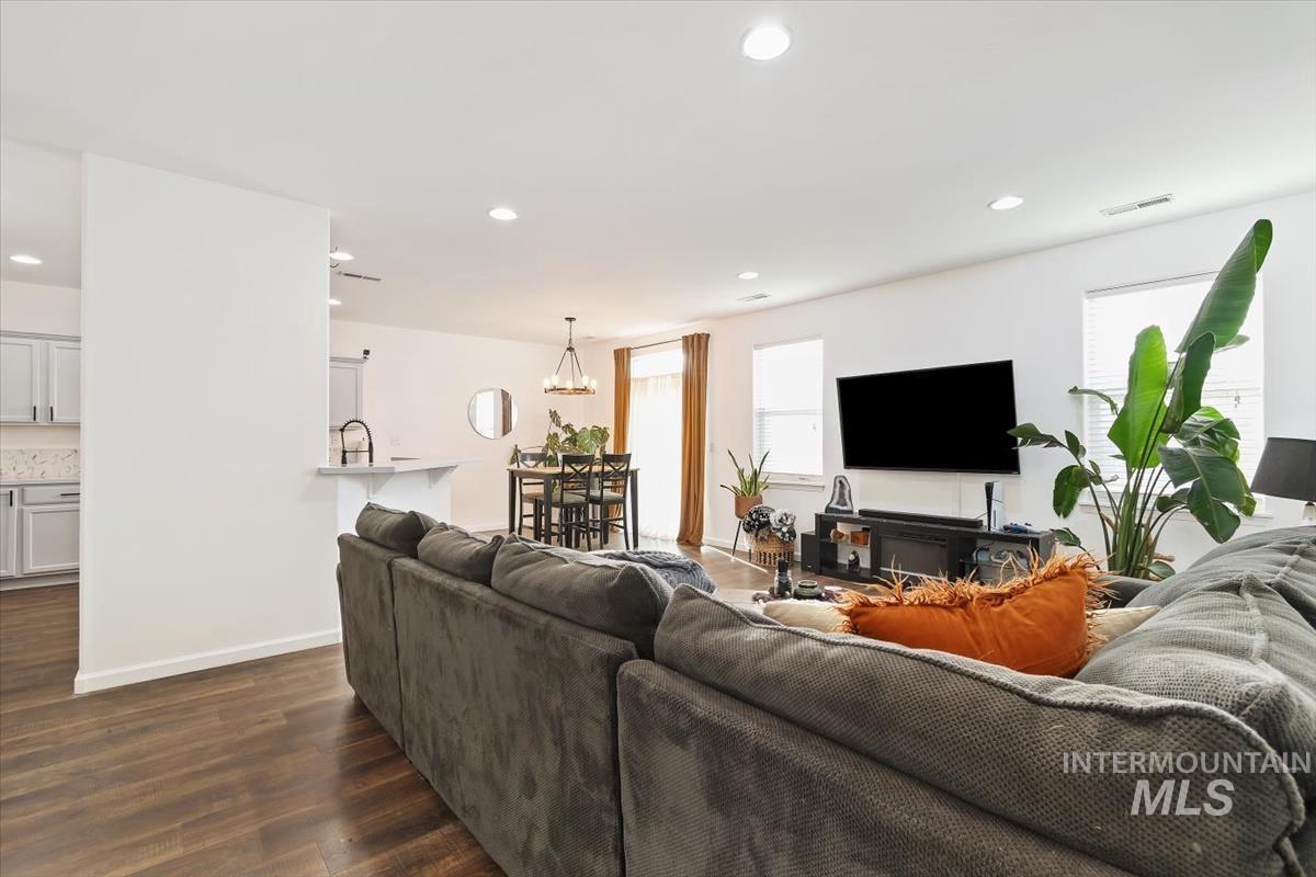 Living room with recessed lighting, dark wood-type flooring, and a chandelier