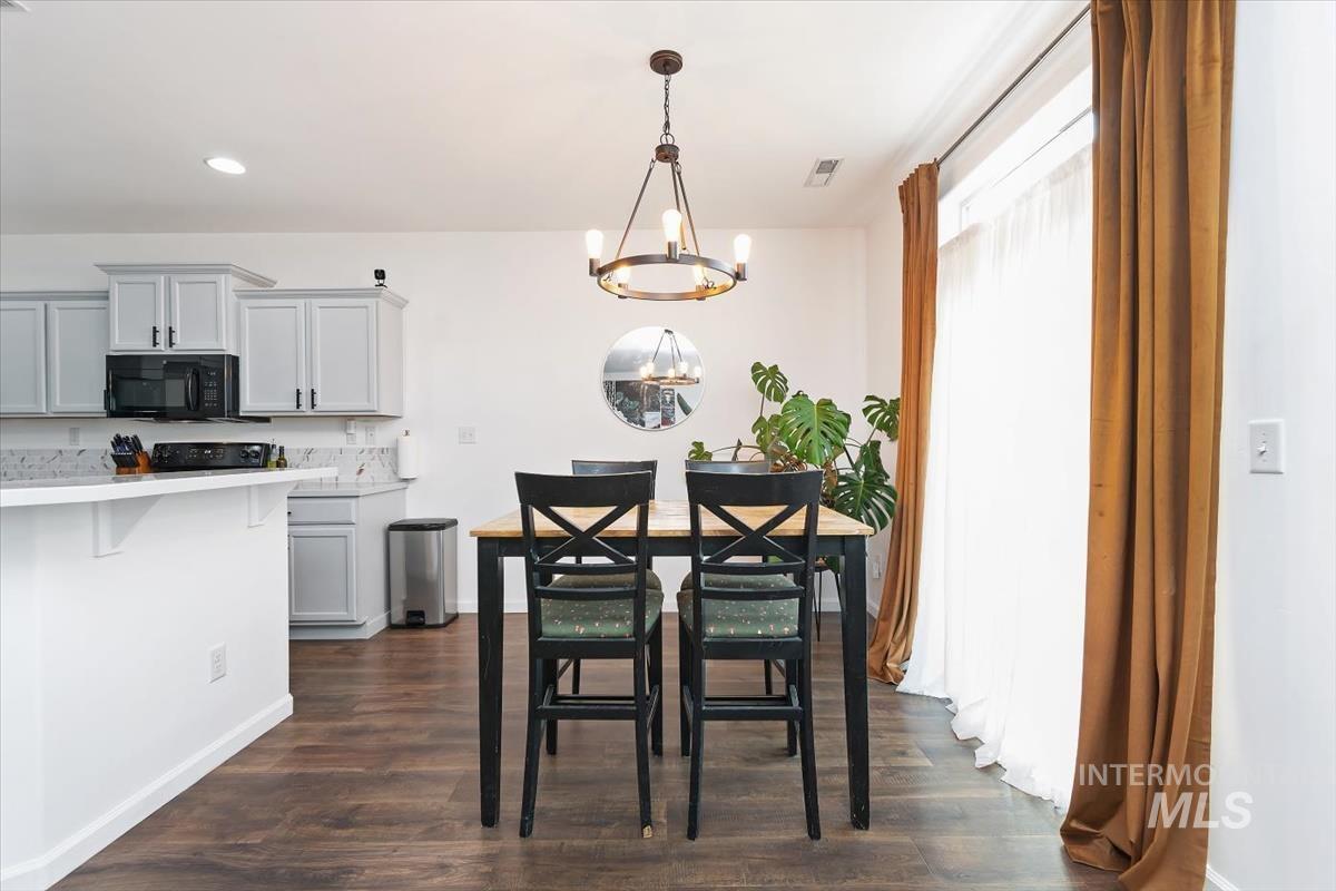 Dining space featuring dark wood-style floors, a chandelier, and recessed lighting