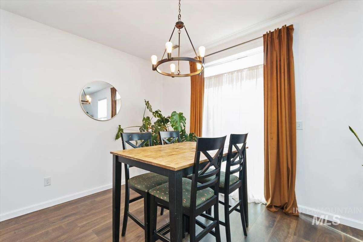 Dining area featuring dark wood-style flooring and a chandelier