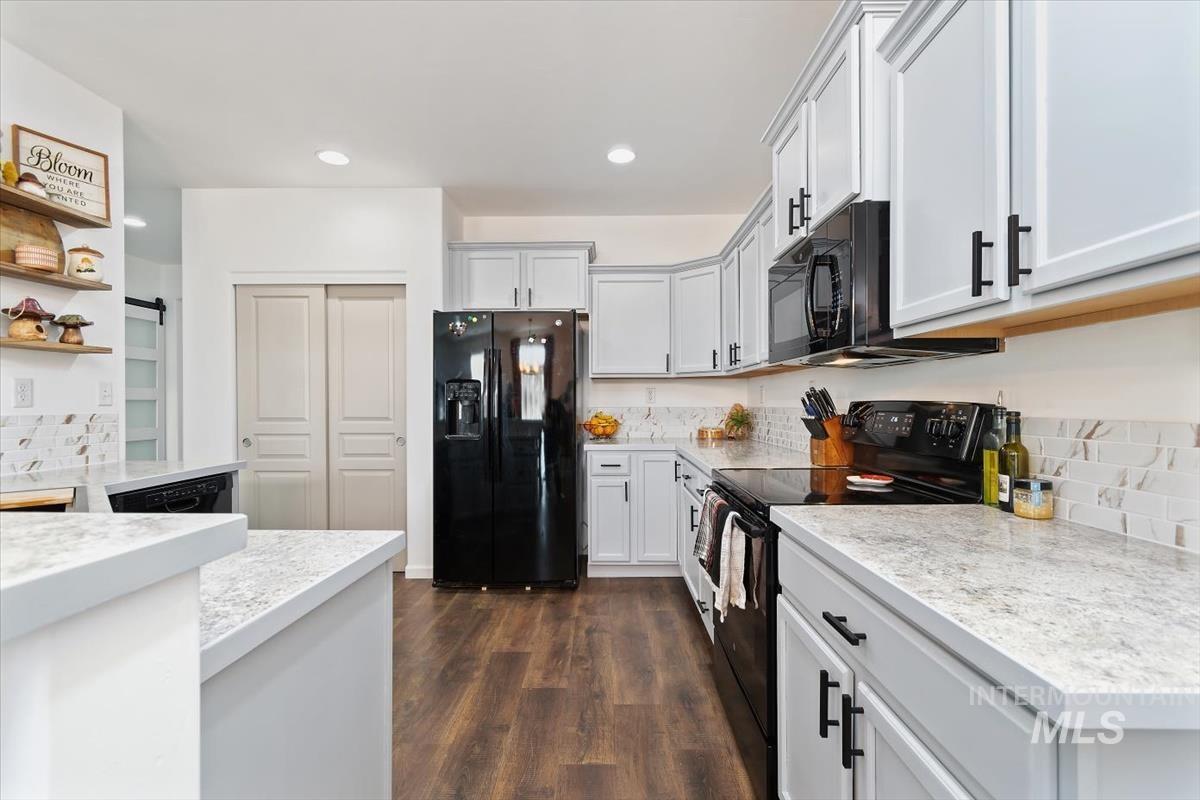 Kitchen featuring black appliances, dark wood-style floors, recessed lighting, light stone counters, and white cabinetry