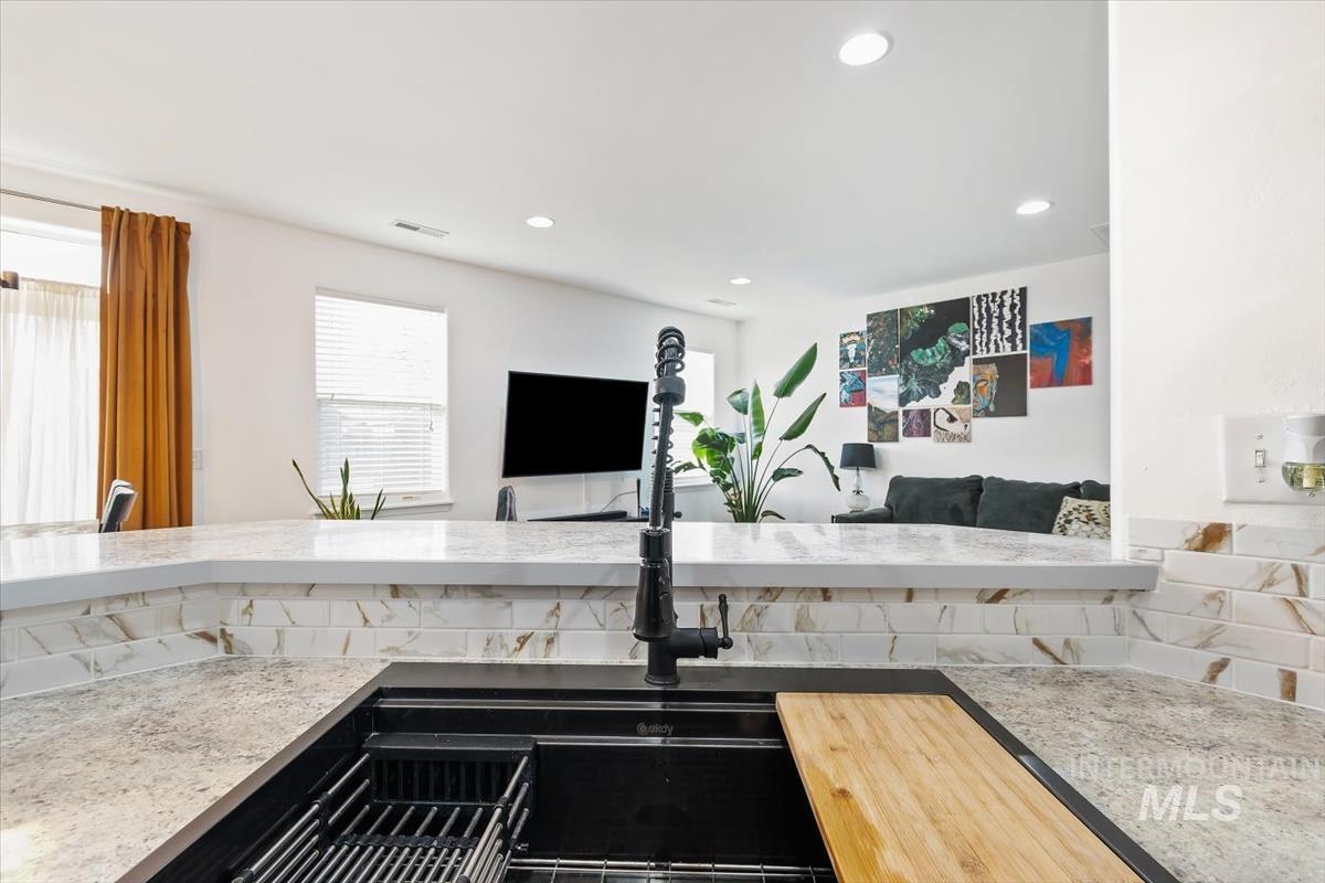 Kitchen featuring light stone countertops, open floor plan, and recessed lighting