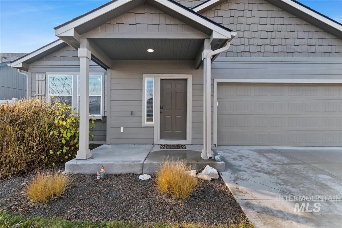 Property entrance with concrete driveway, an attached garage, and covered porch