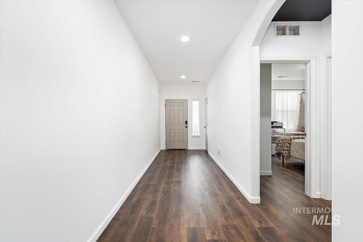 Hall featuring arched walkways, recessed lighting, and dark wood-style floors
