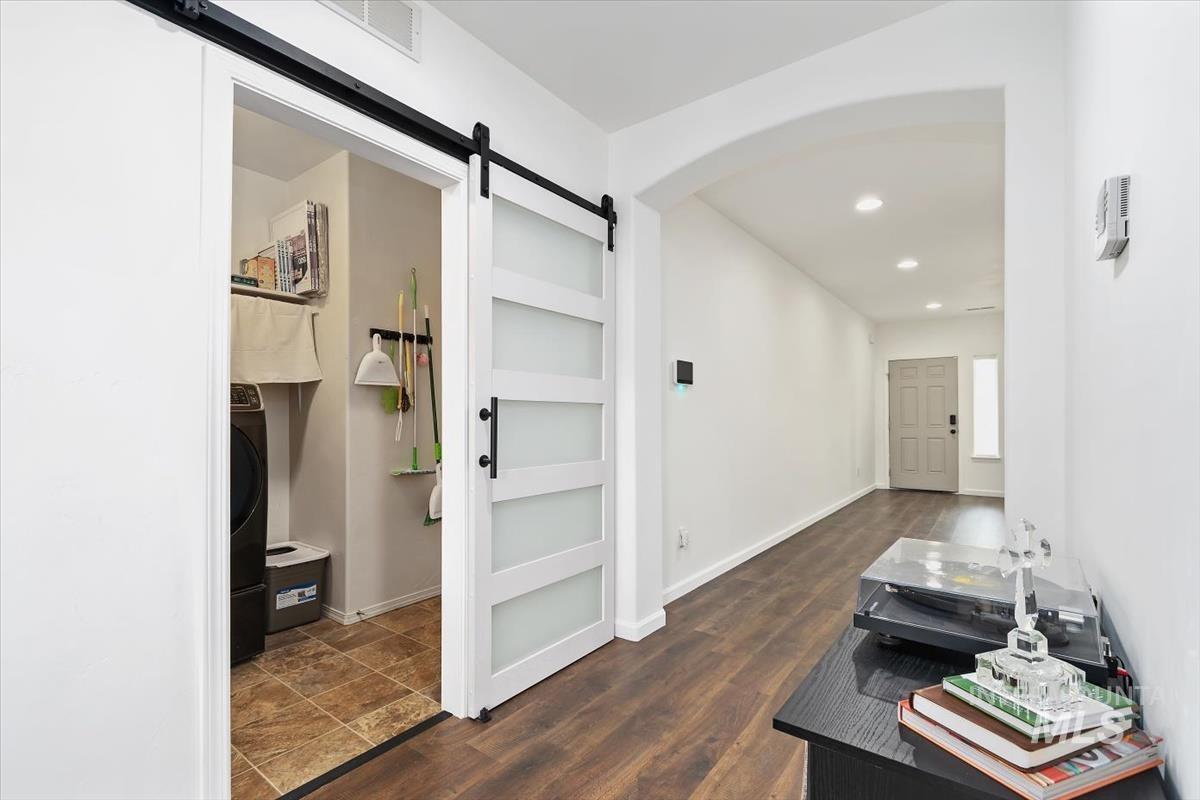 Hallway with dark wood-style flooring, arched walkways, a barn door, recessed lighting, and washer / clothes dryer