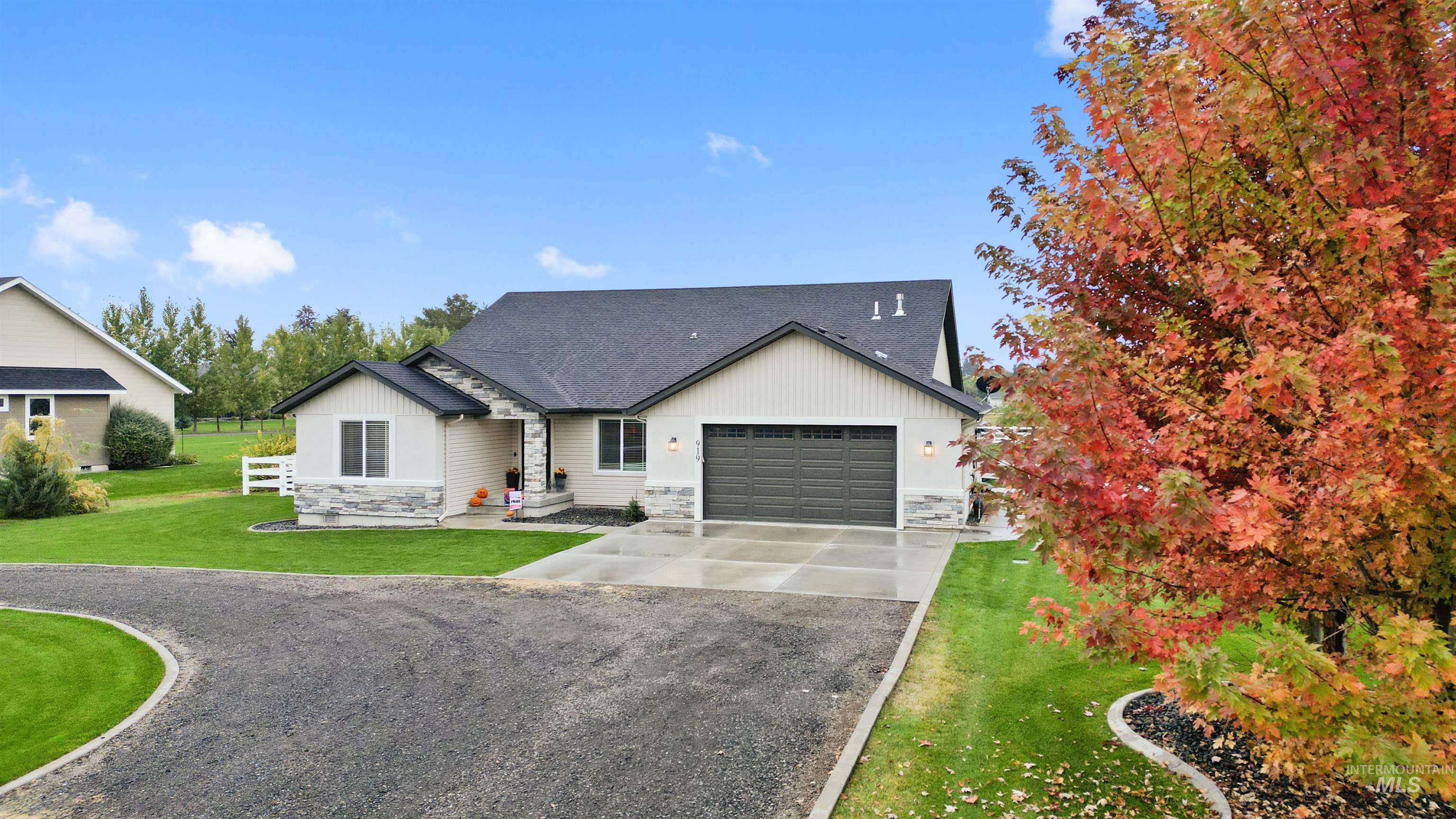 View of front facade with stone siding, driveway, a front lawn, a shingled roof, and a garage