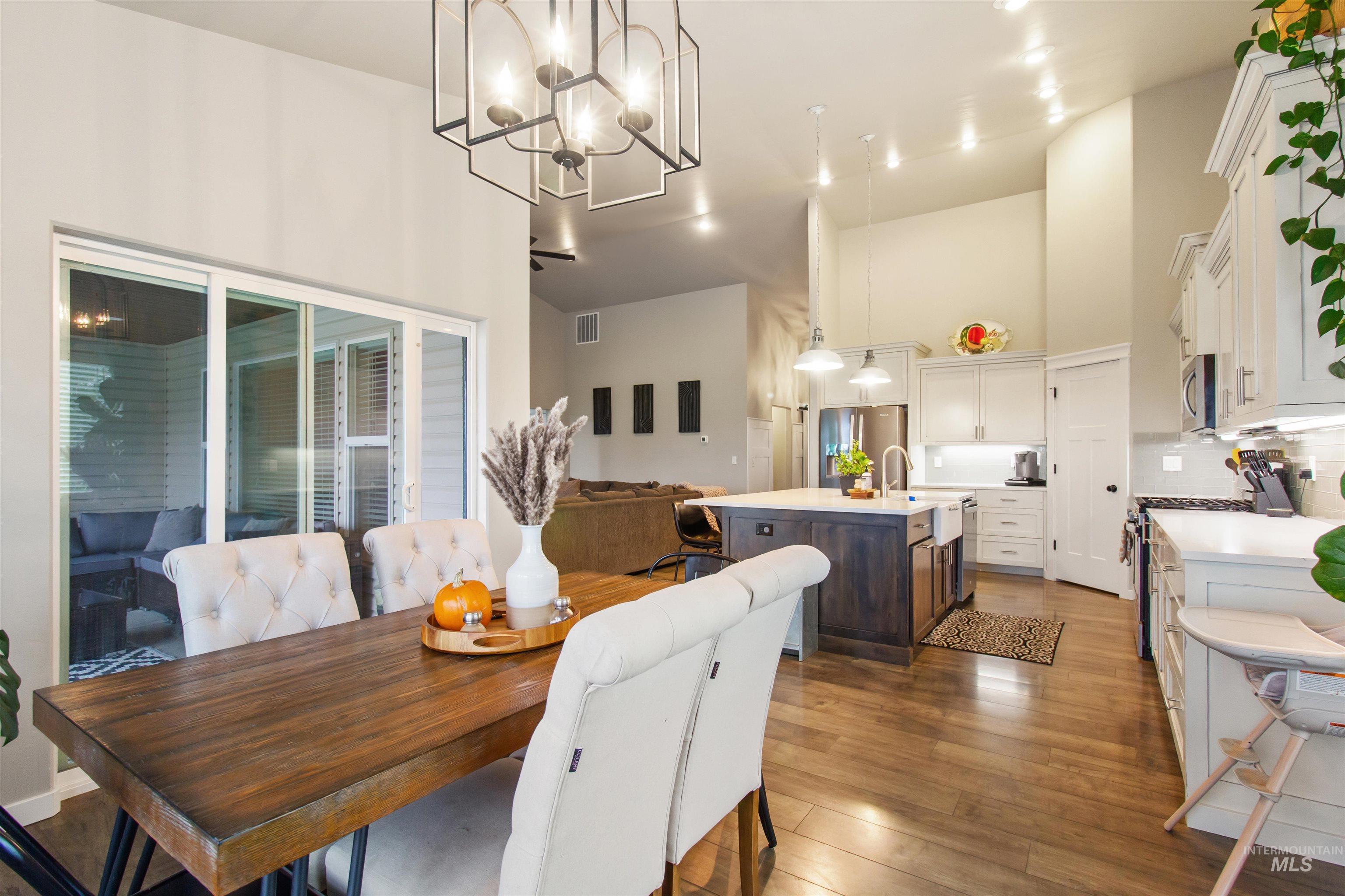 Dining space featuring high vaulted ceiling, dark wood-type flooring, and a chandelier