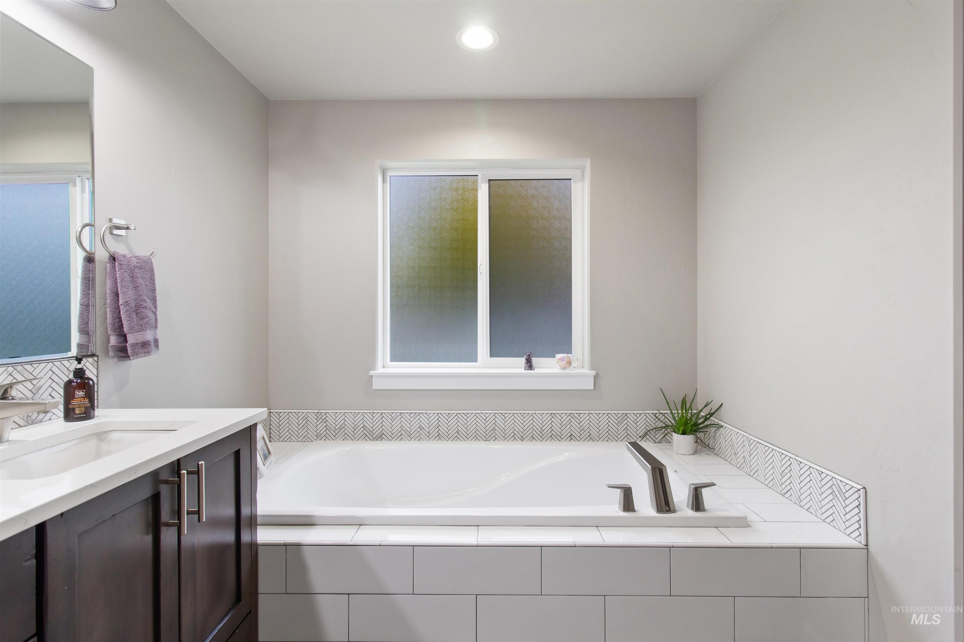 Bathroom featuring vanity, a garden tub, recessed lighting, and healthy amount of natural light