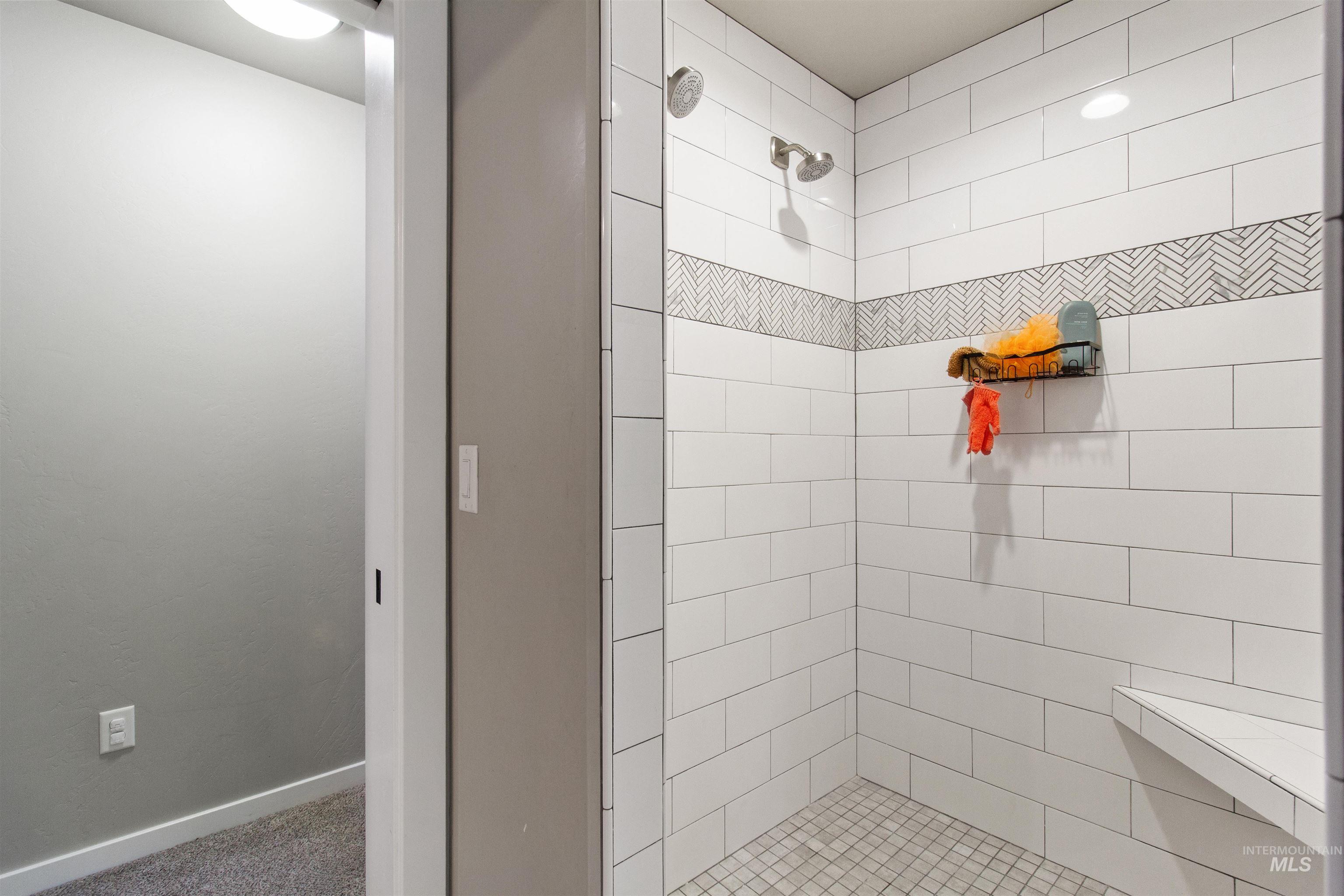 Bathroom with tiled shower and baseboards