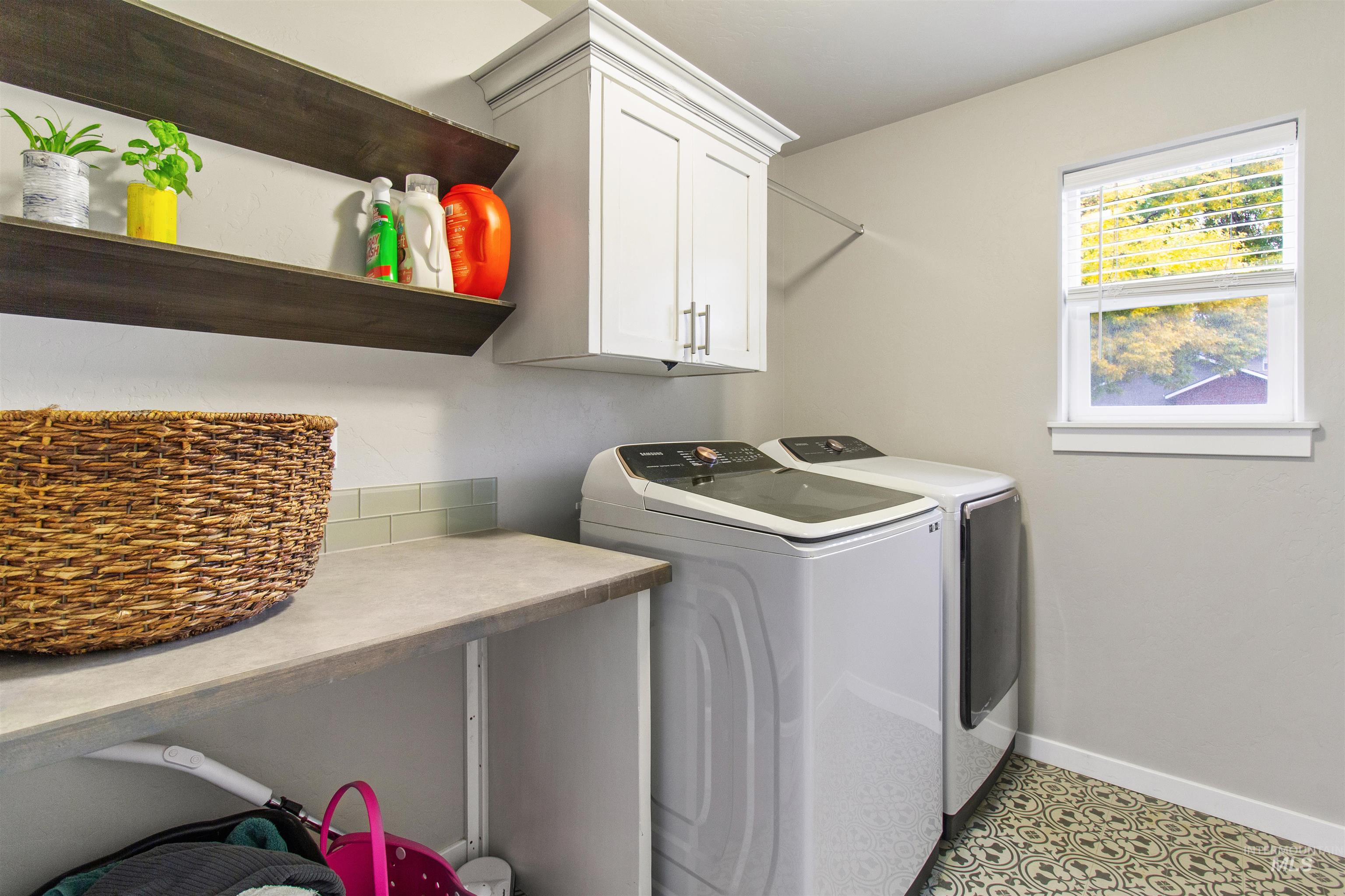 Washroom featuring cabinet space, washer and dryer, and light tile patterned floors