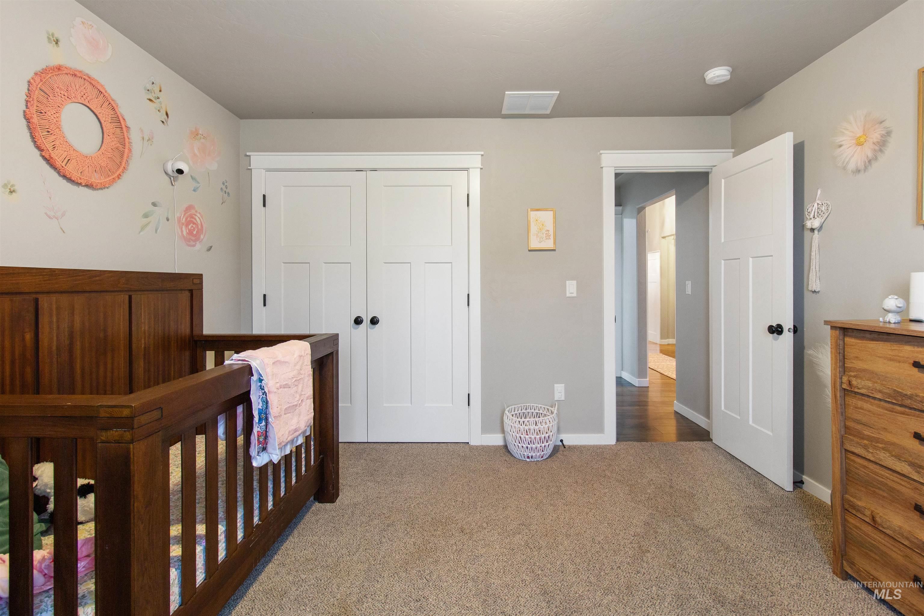 Bedroom with carpet, a nursery area, and a closet