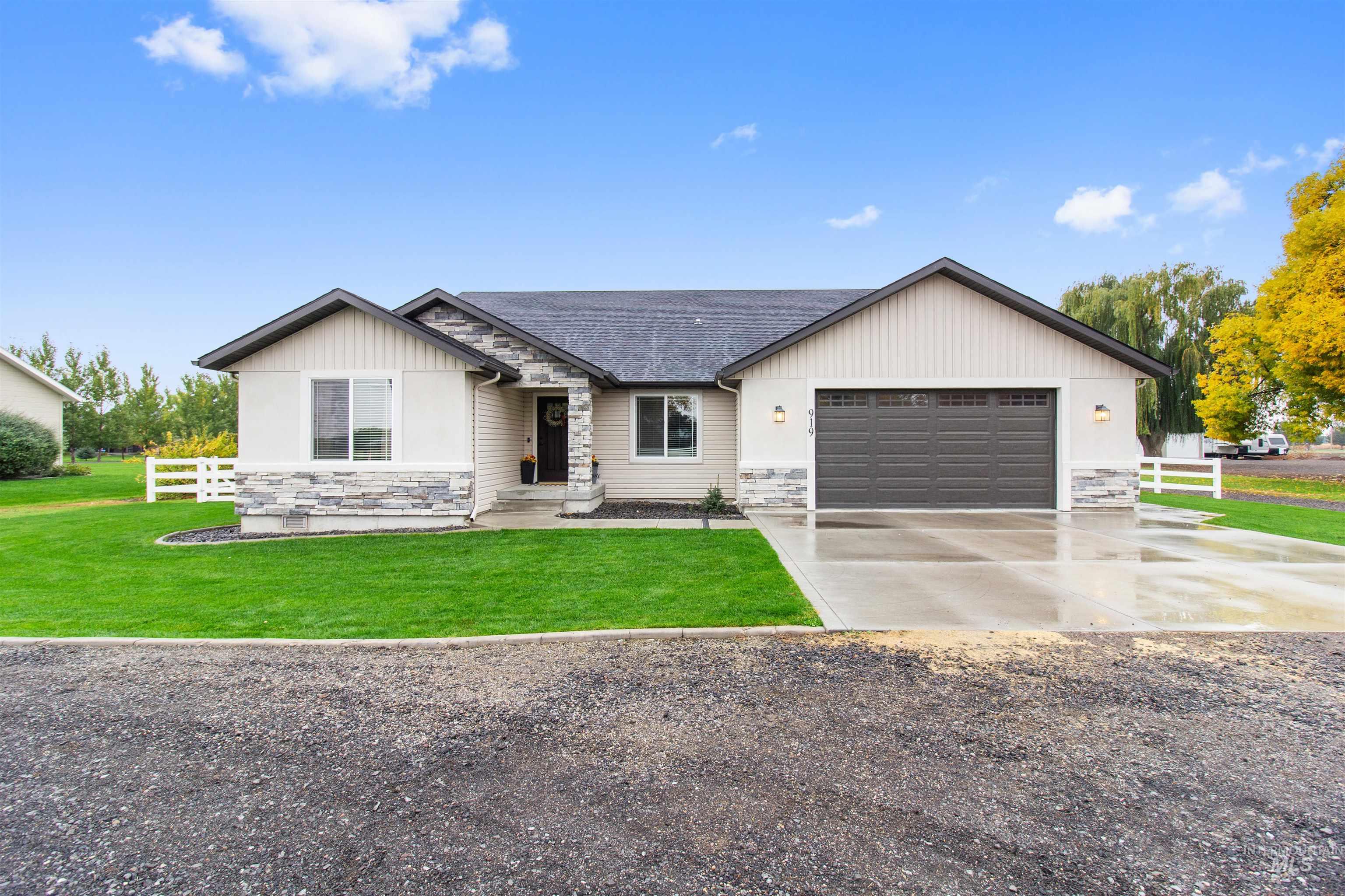 View of front of home with stone siding, concrete driveway, an attached garage, and board and batten siding