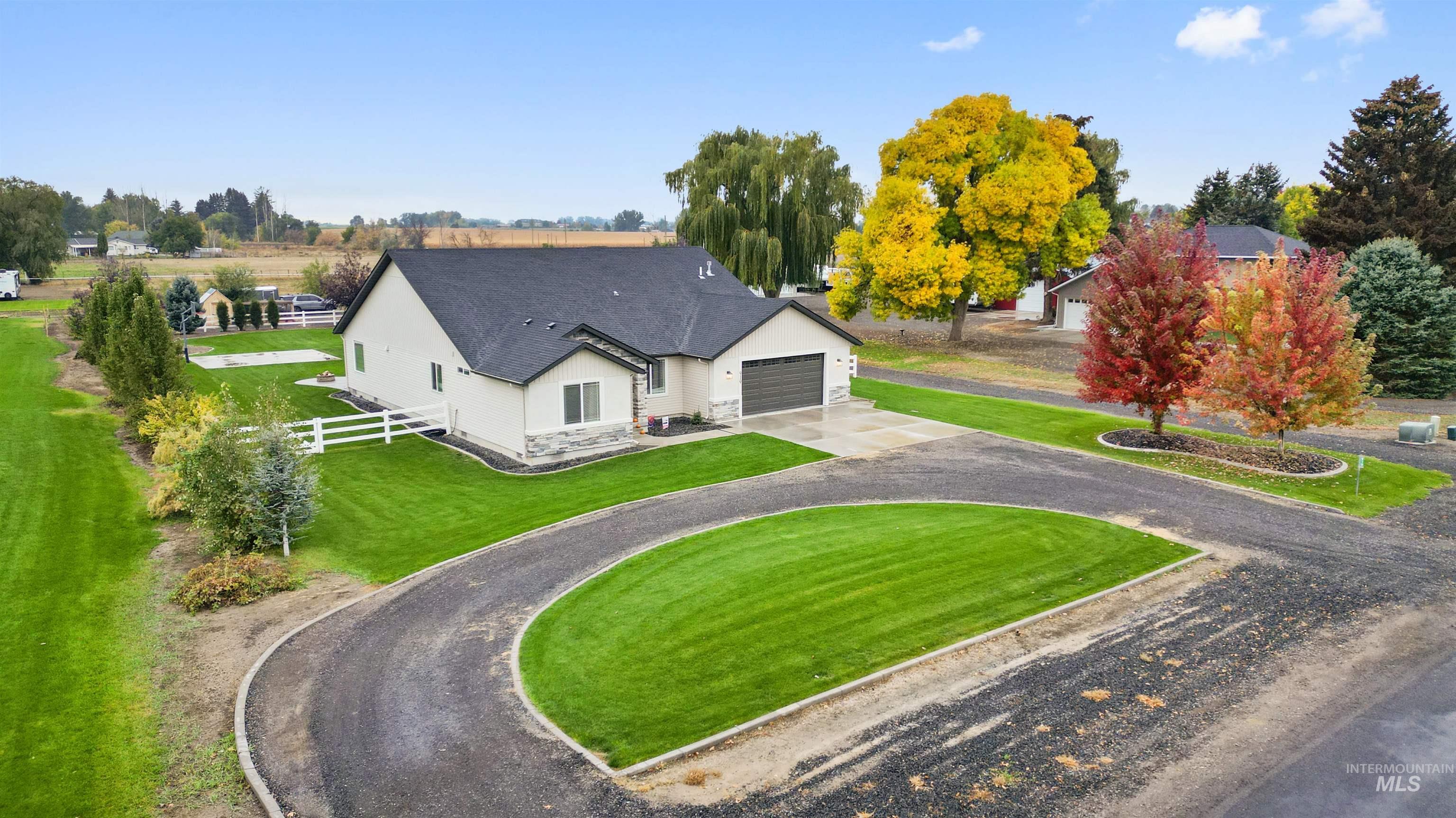 Rear view of property featuring curved driveway, stone siding, a shingled roof, and stucco siding