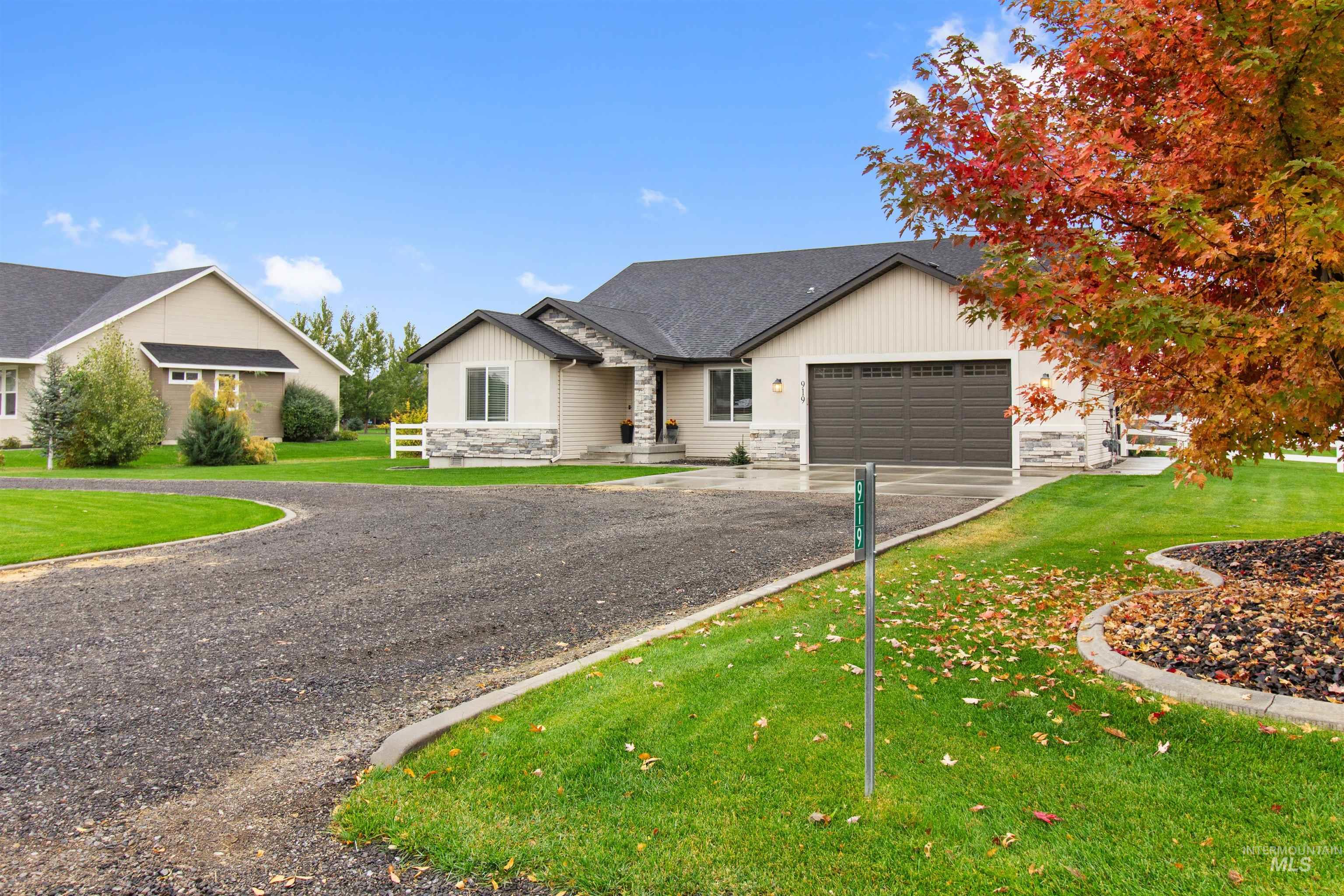 View of front of property featuring stone siding, driveway, a front lawn, roof with shingles, and an attached garage