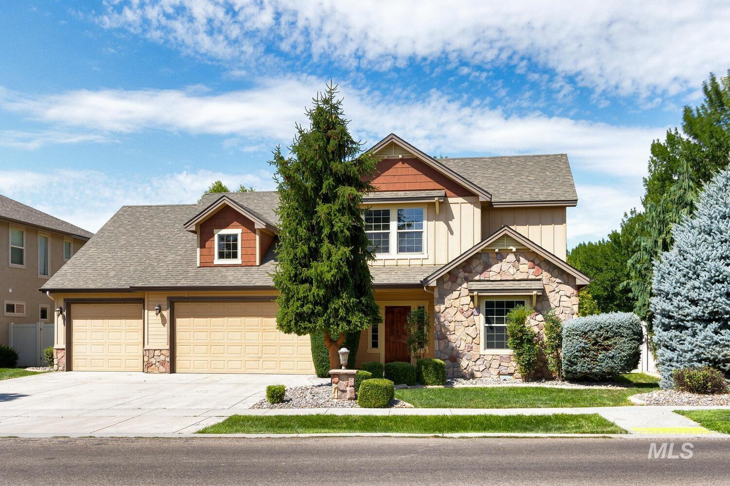 Craftsman-style house with stone siding, concrete driveway, roof with shingles, and board and batten siding