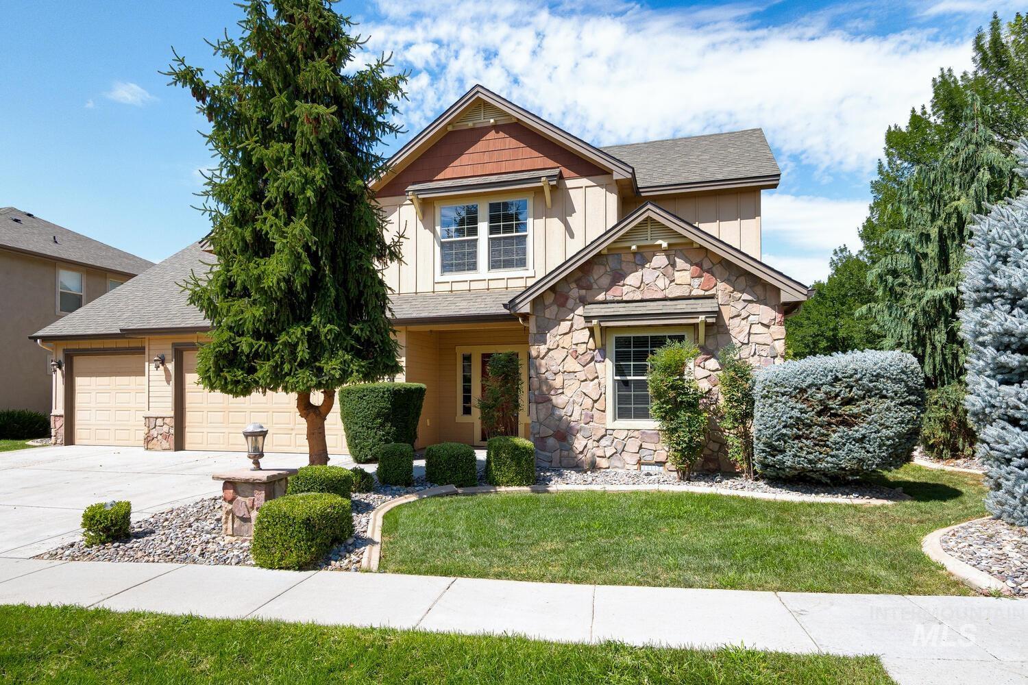 Craftsman house with stone siding, board and batten siding, driveway, a front lawn, and a shingled roof