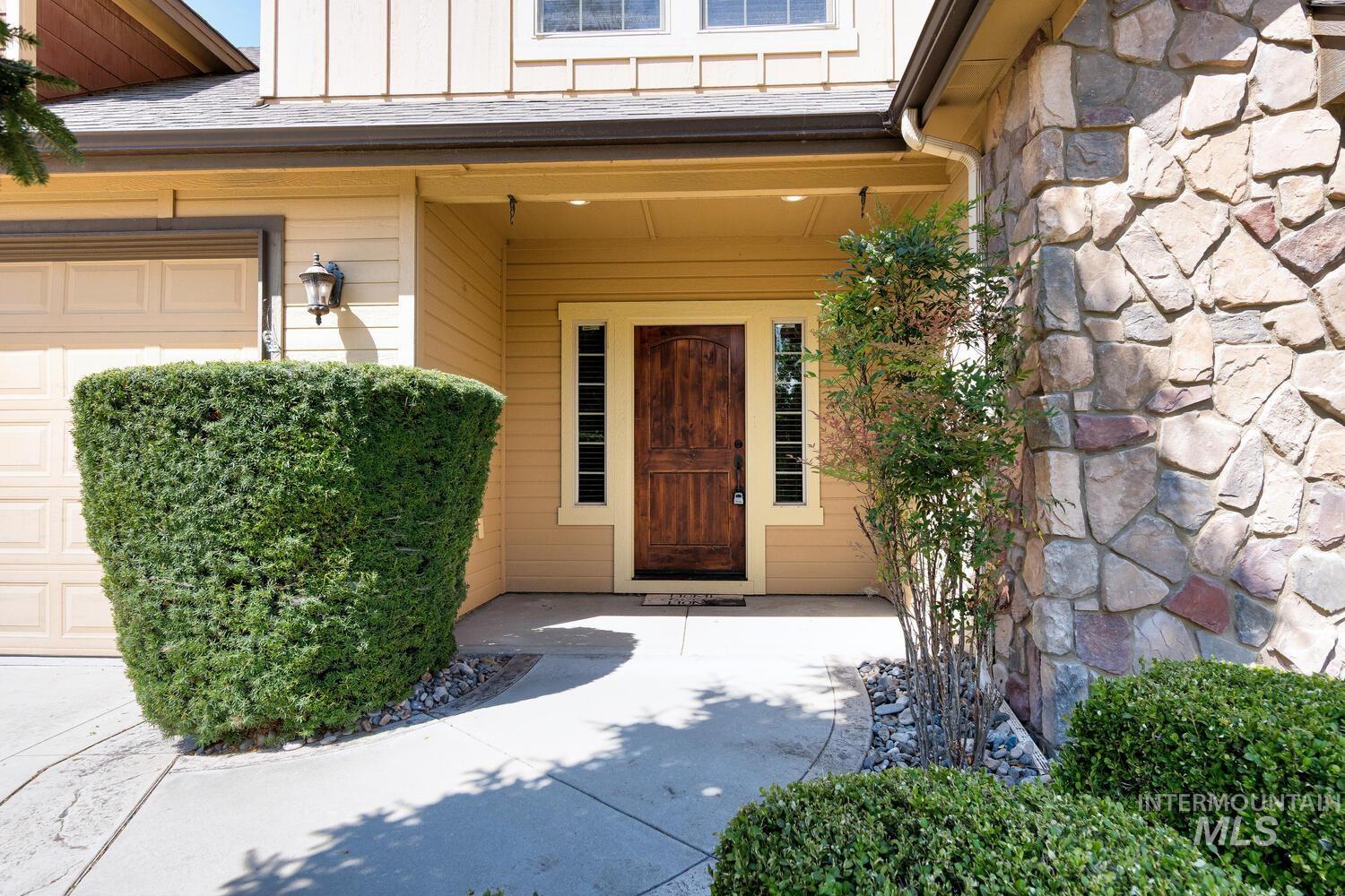 Entrance to property with stone siding, board and batten siding, and covered porch