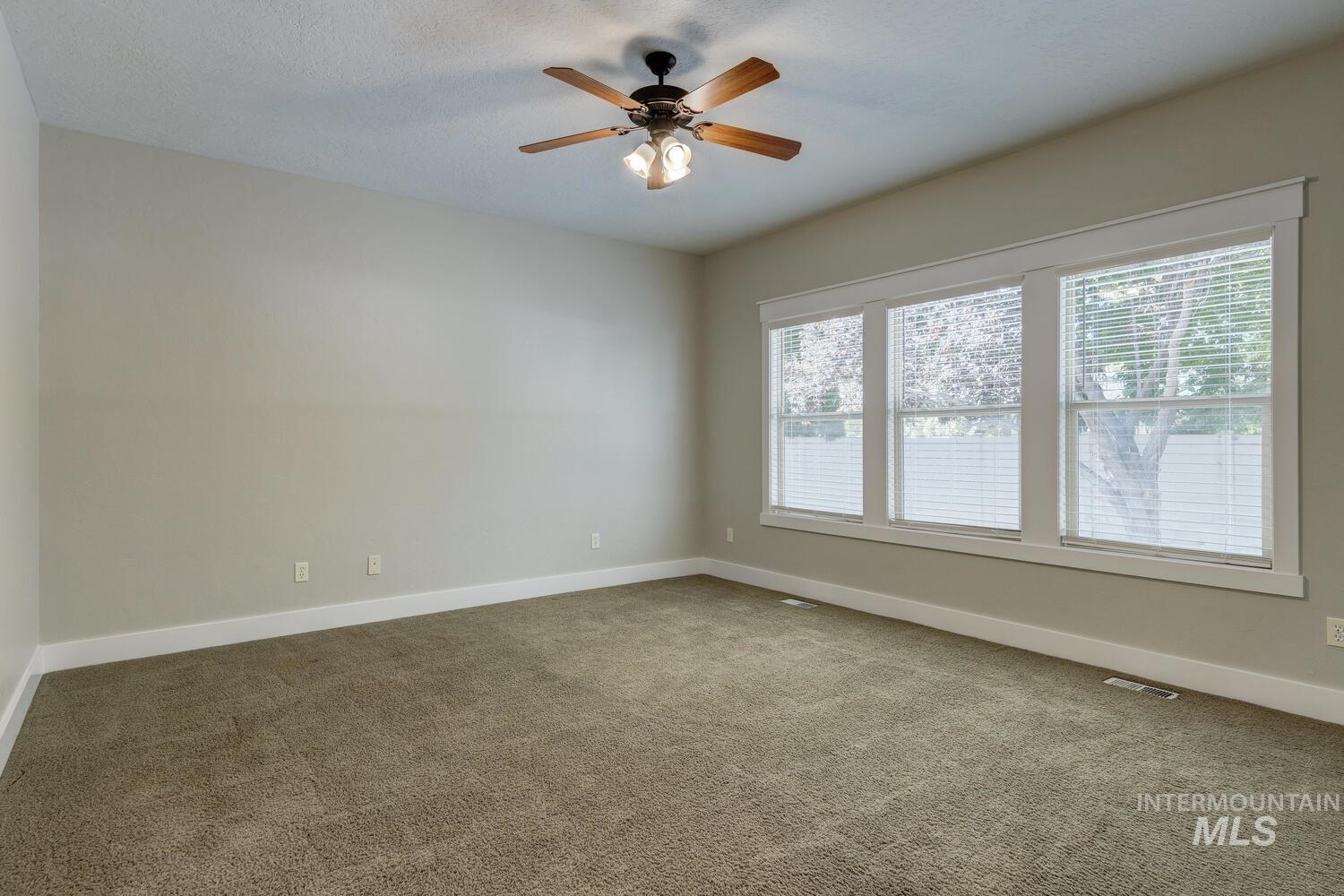 Empty room featuring carpet floors and a ceiling fan