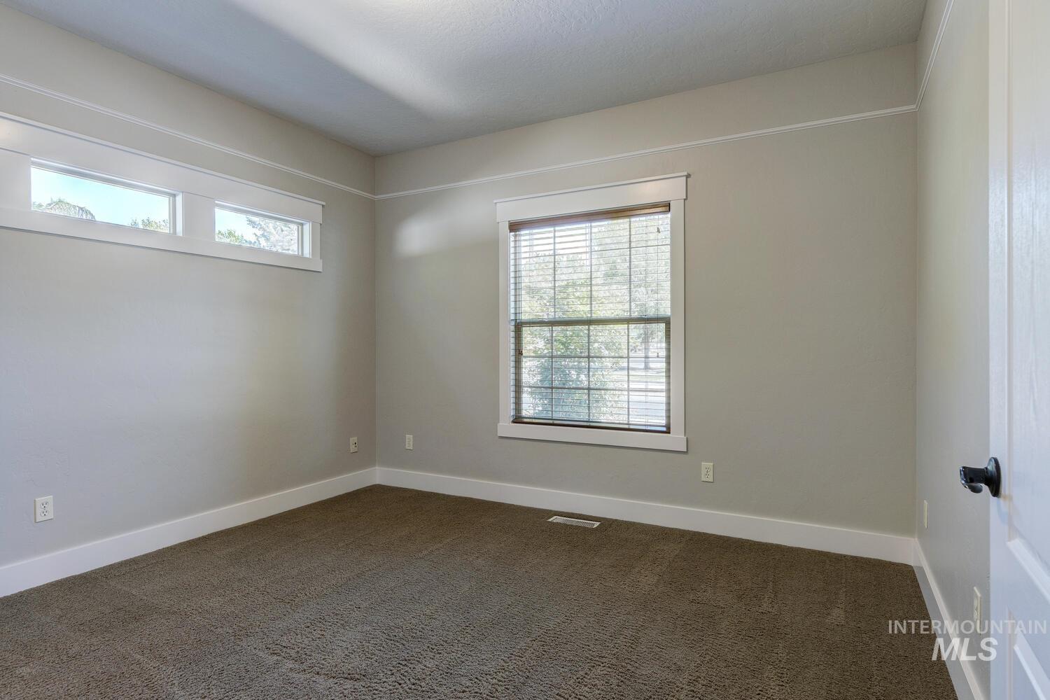 Unfurnished room with dark carpet and baseboards