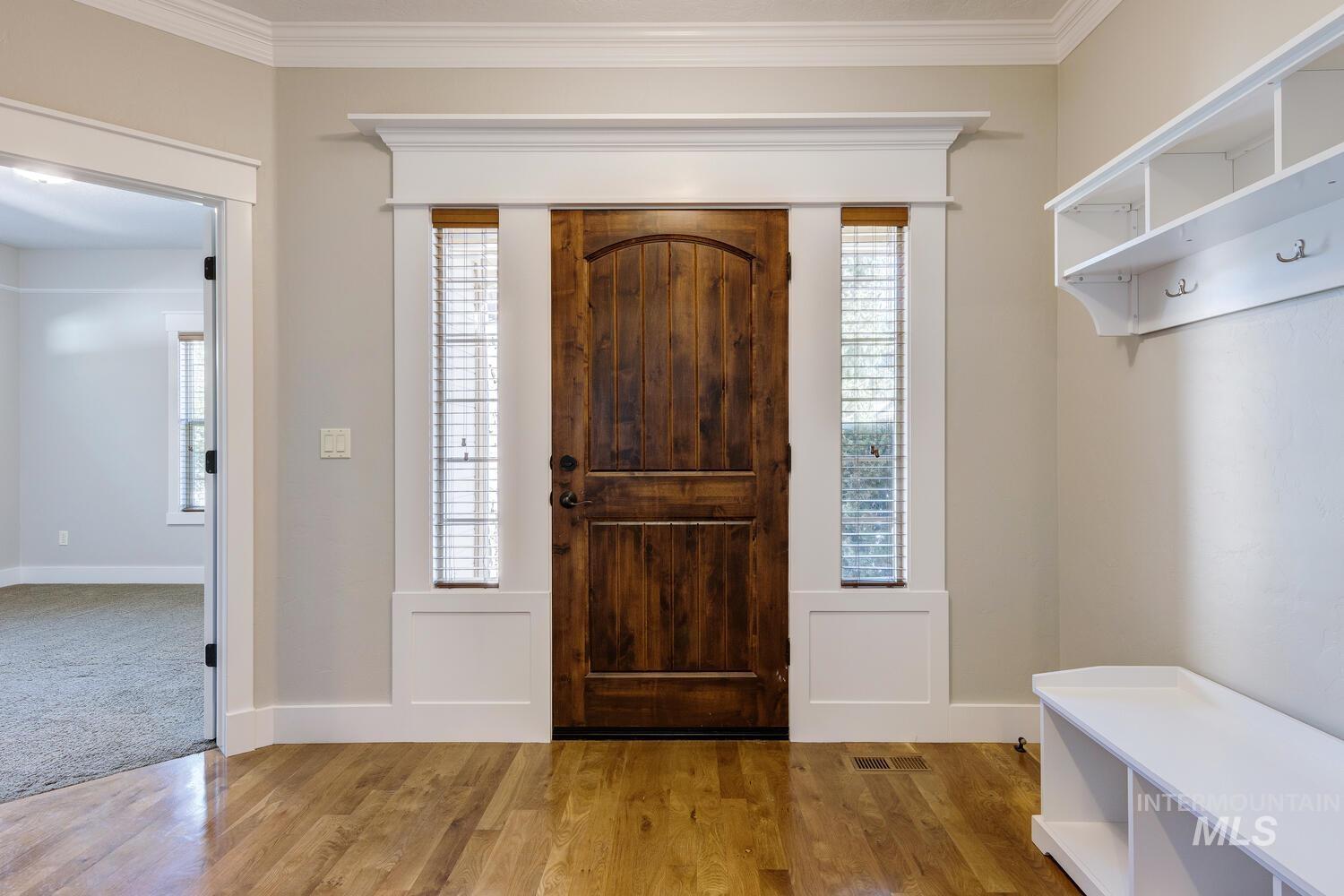 Foyer featuring wood finished floors and crown molding