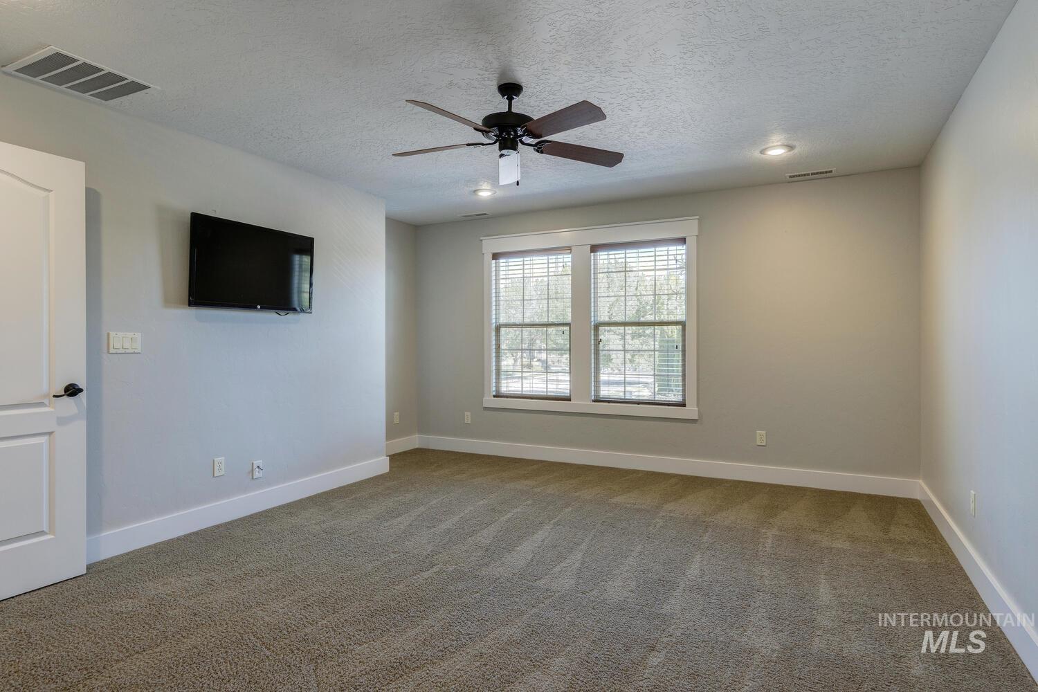 Empty room with light colored carpet, ceiling fan, a textured ceiling, and recessed lighting