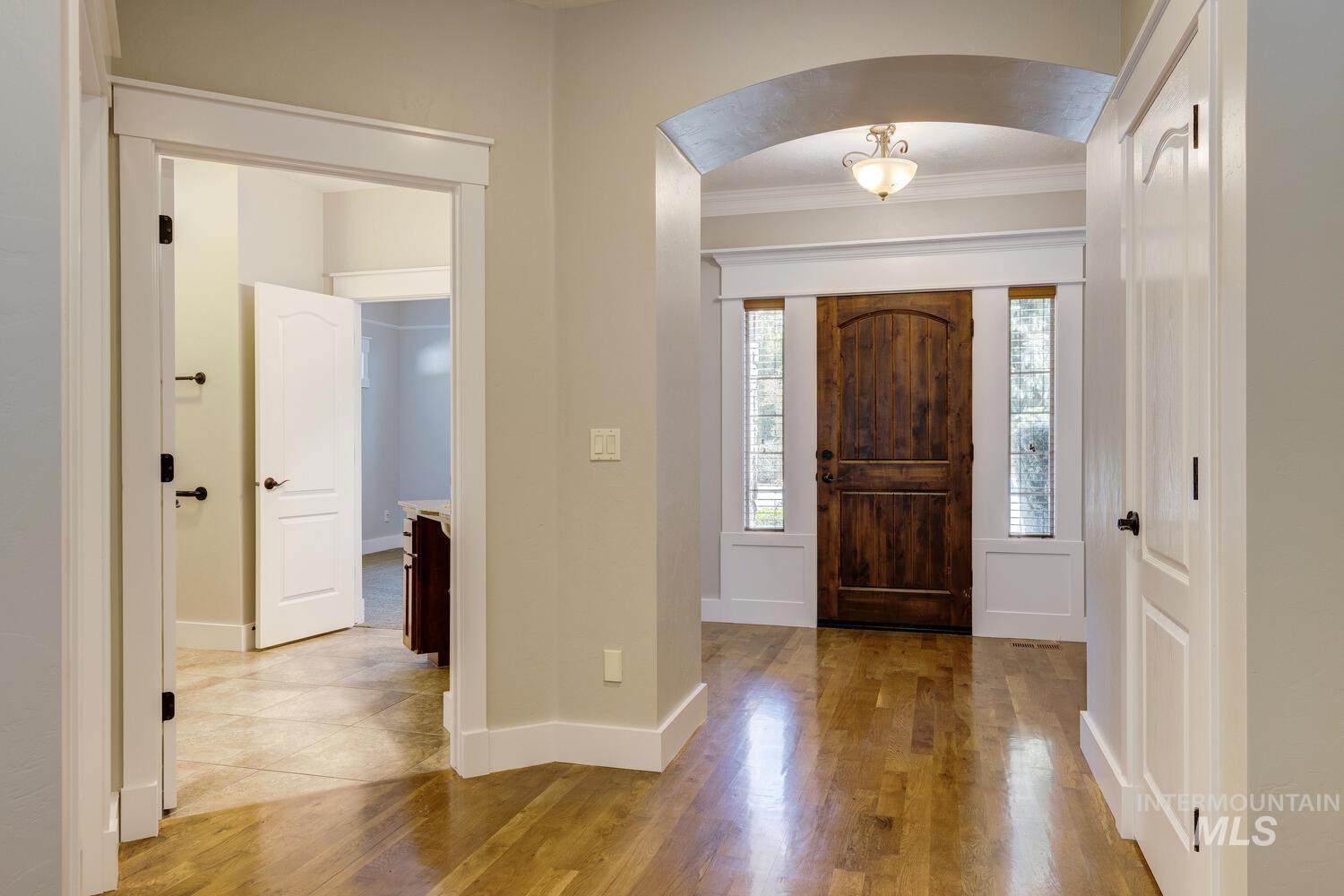 Entrance foyer featuring ornamental molding, arched walkways, and light wood-type flooring
