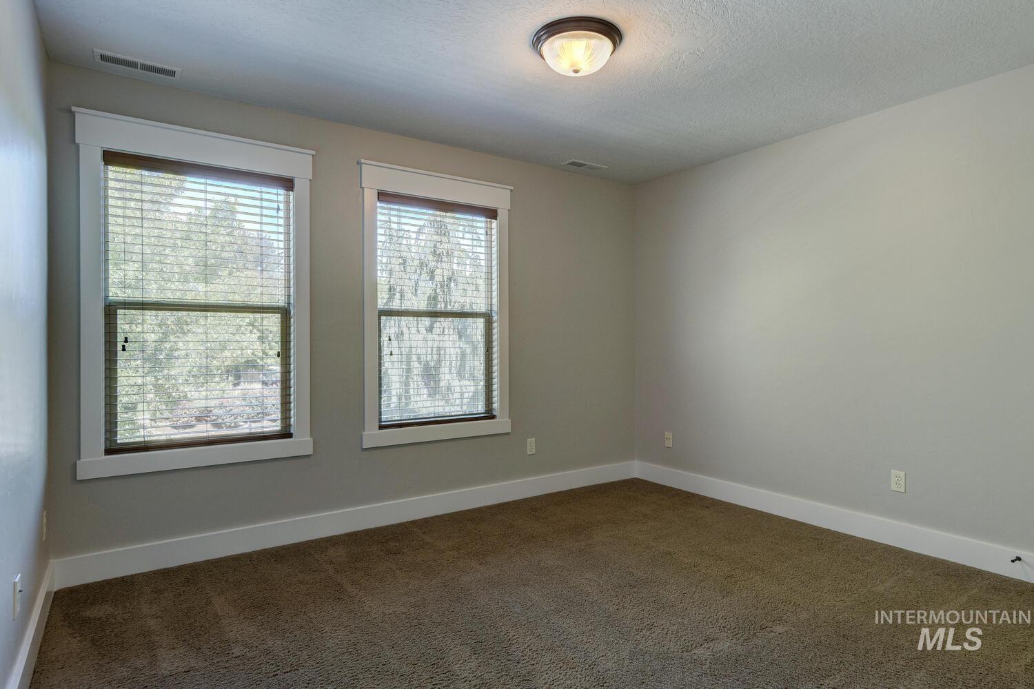Unfurnished room featuring dark colored carpet and a textured ceiling