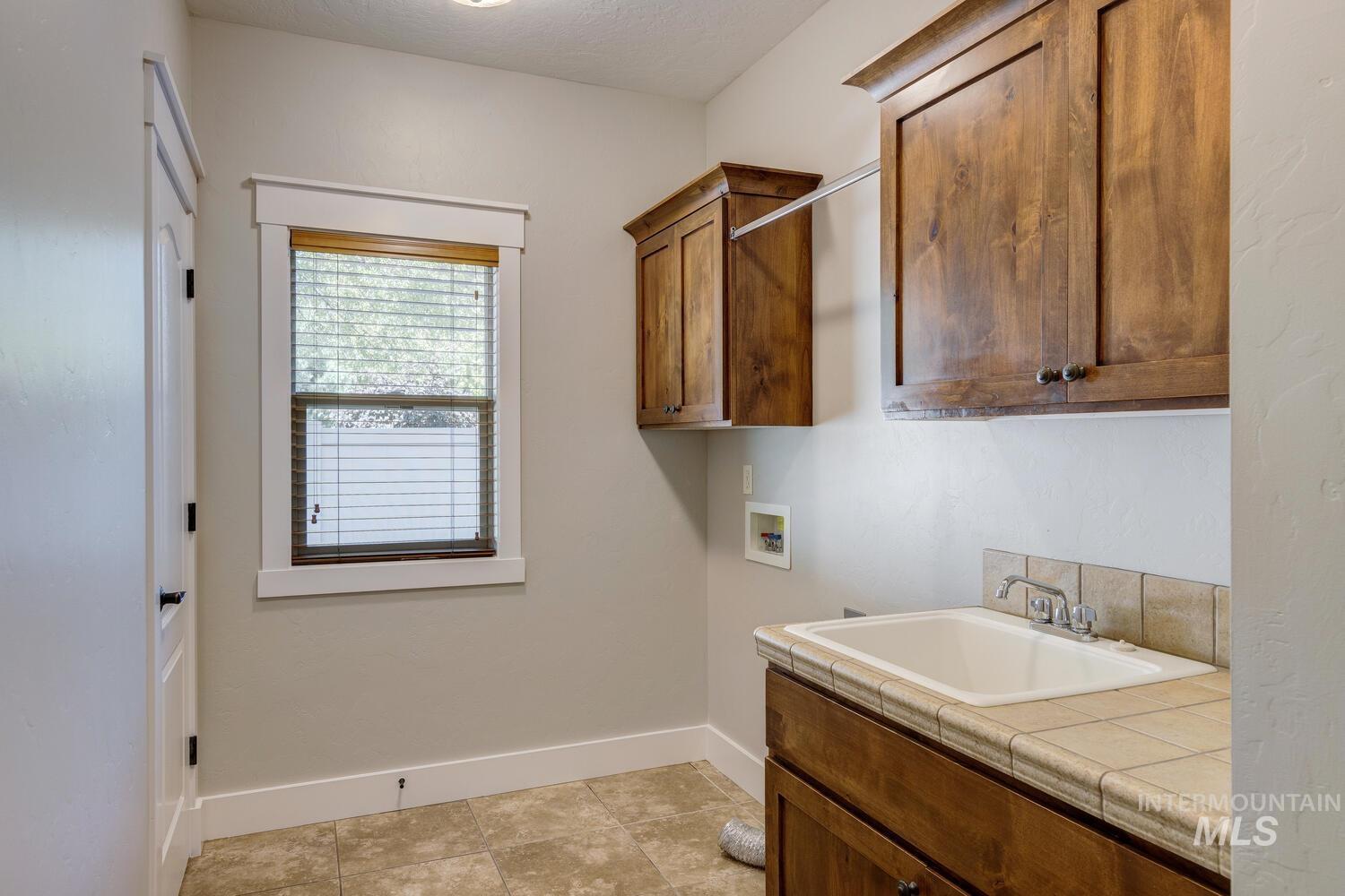 Laundry area featuring washer hookup, cabinet space, and light tile patterned floors