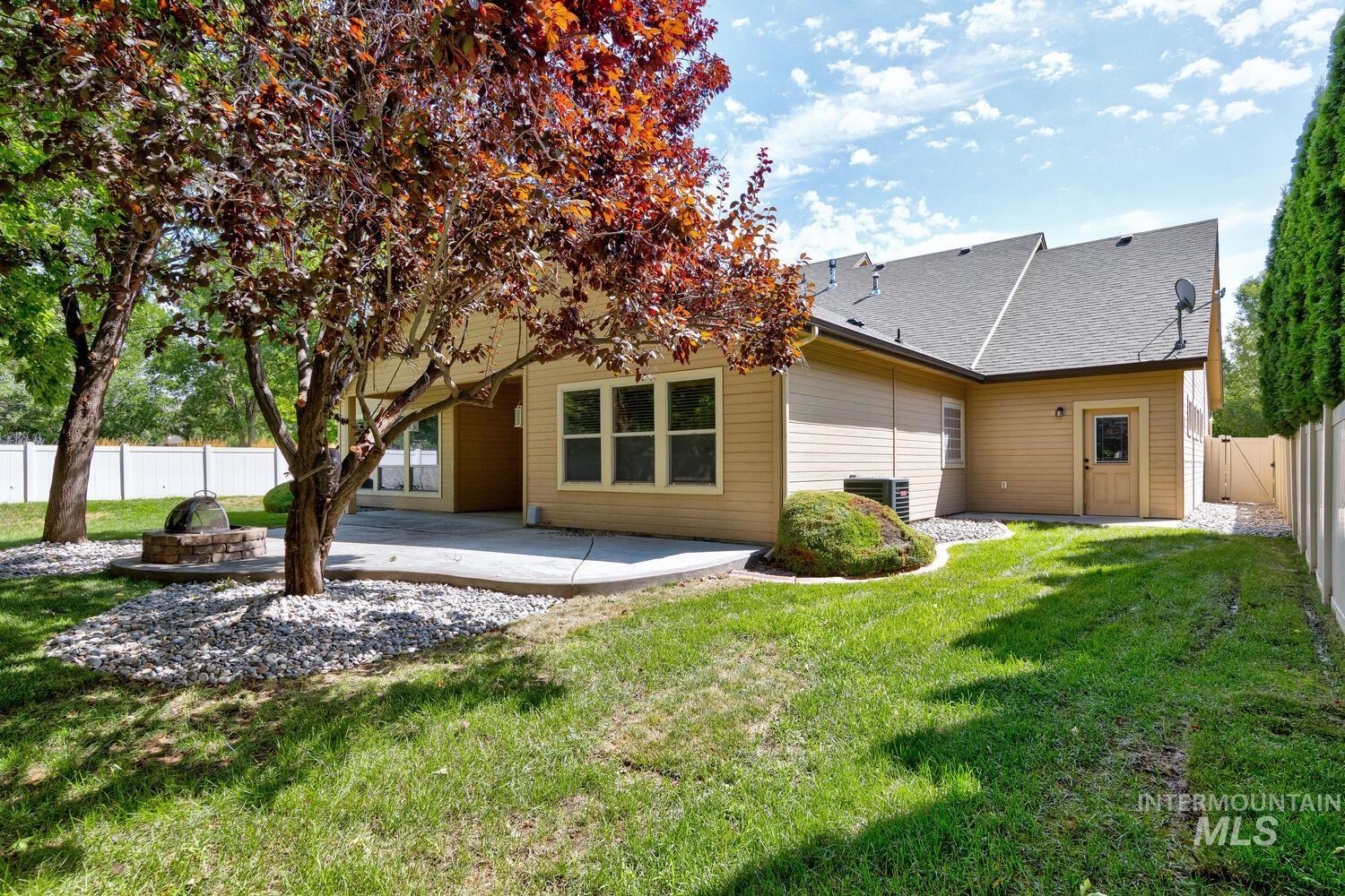 Rear view of property featuring a fenced backyard, a patio, roof with shingles, and a fire pit