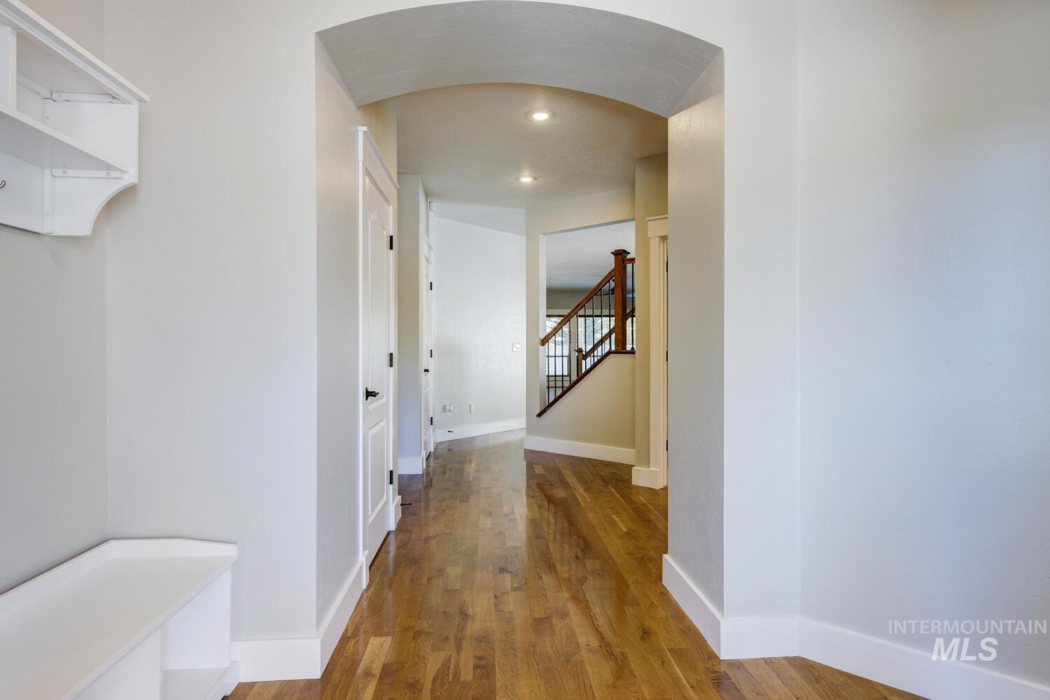 Corridor featuring arched walkways, dark wood-type flooring, stairway, and recessed lighting
